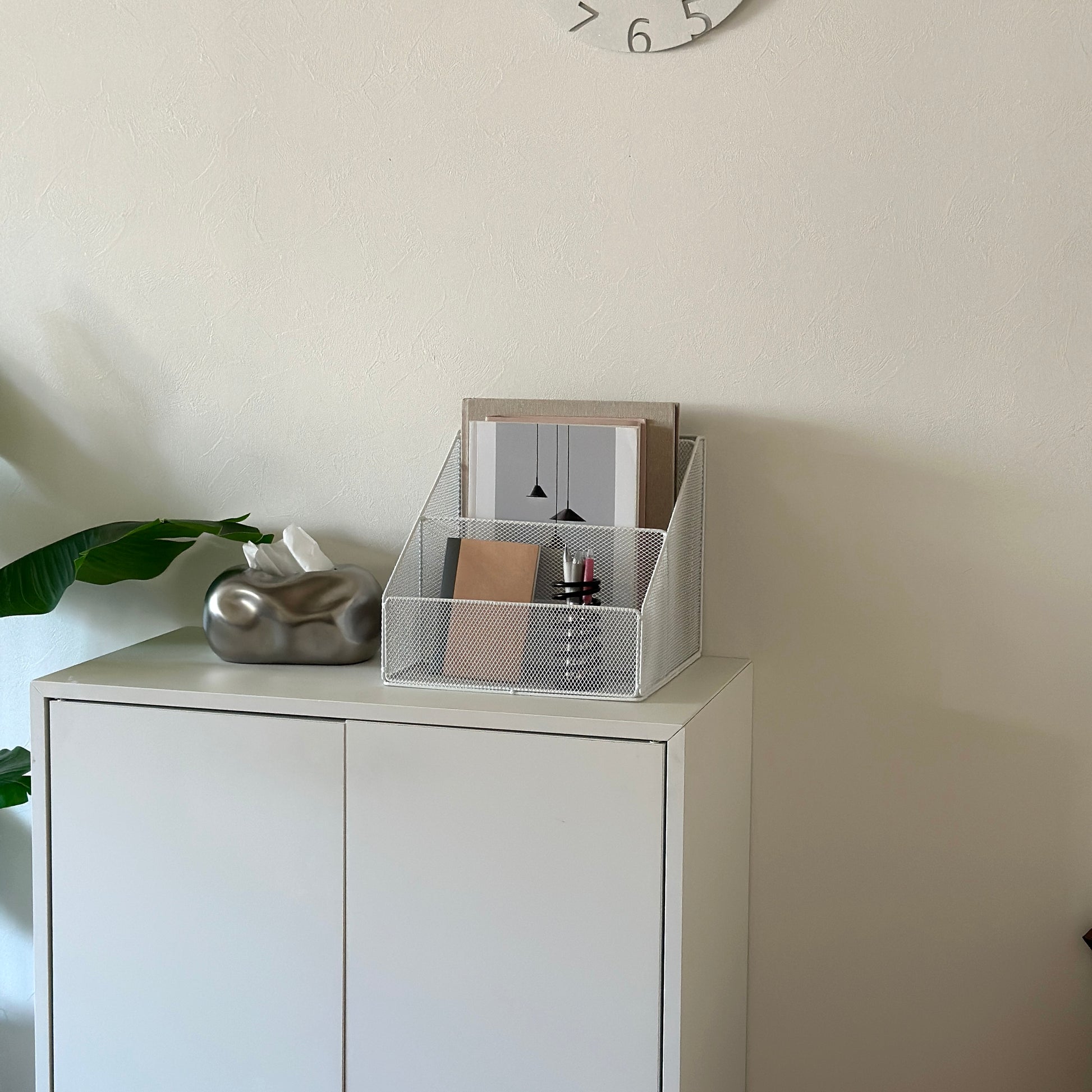 ホワイトのアイアン素材のメッシュ収納ラックを白棚の上に置いている様子