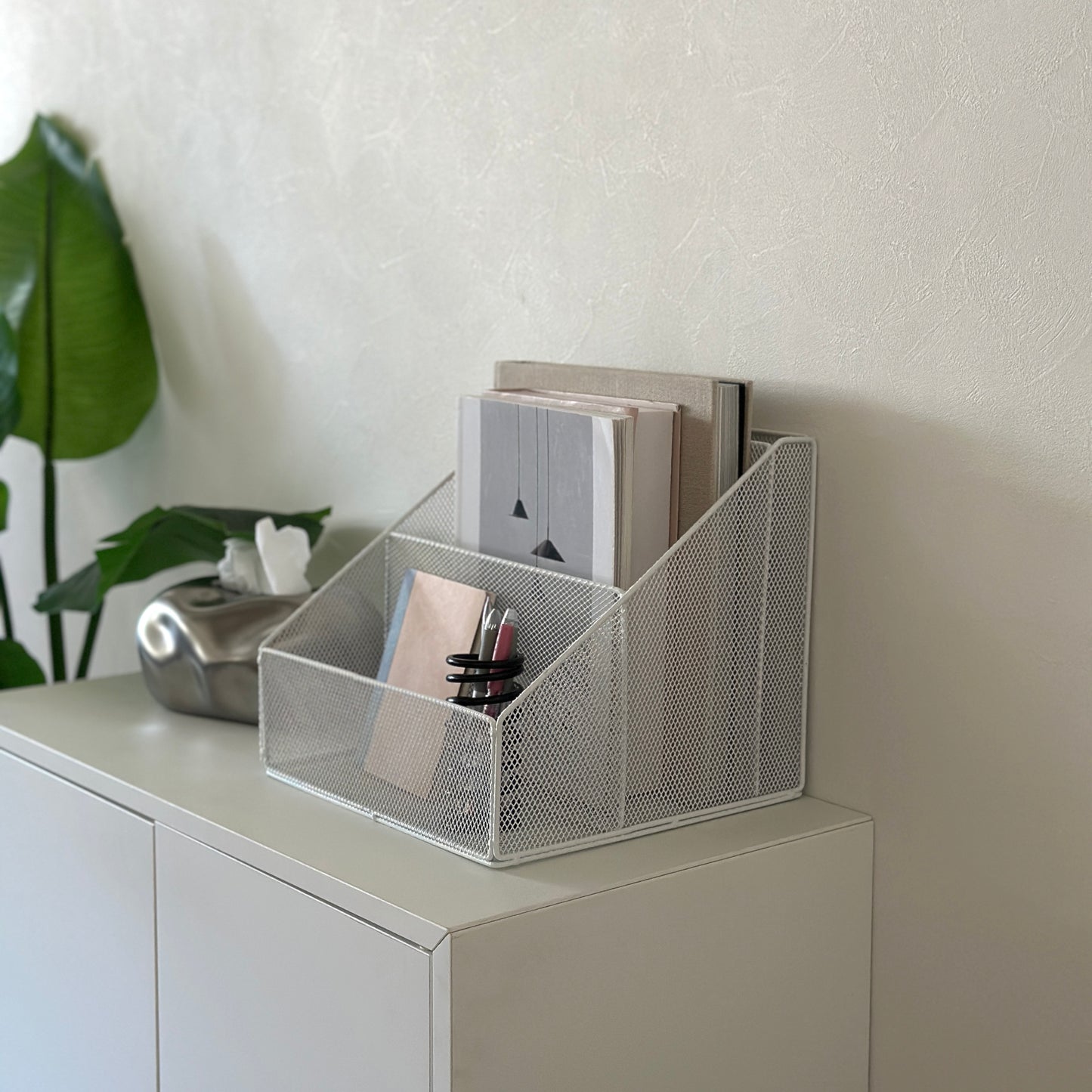 ホワイトのアイアン素材のメッシュ収納ラックを白棚の上に置いている様子