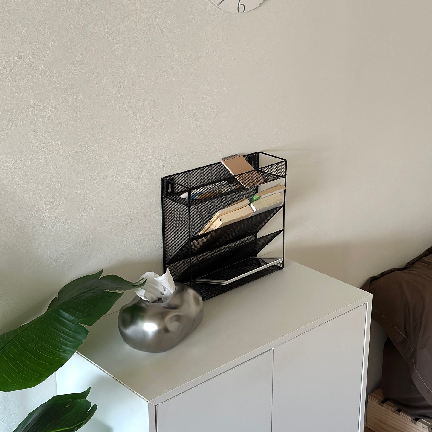 ブラックのメッシュデザインの4段構造ラックが白棚の上に置かれてある様子