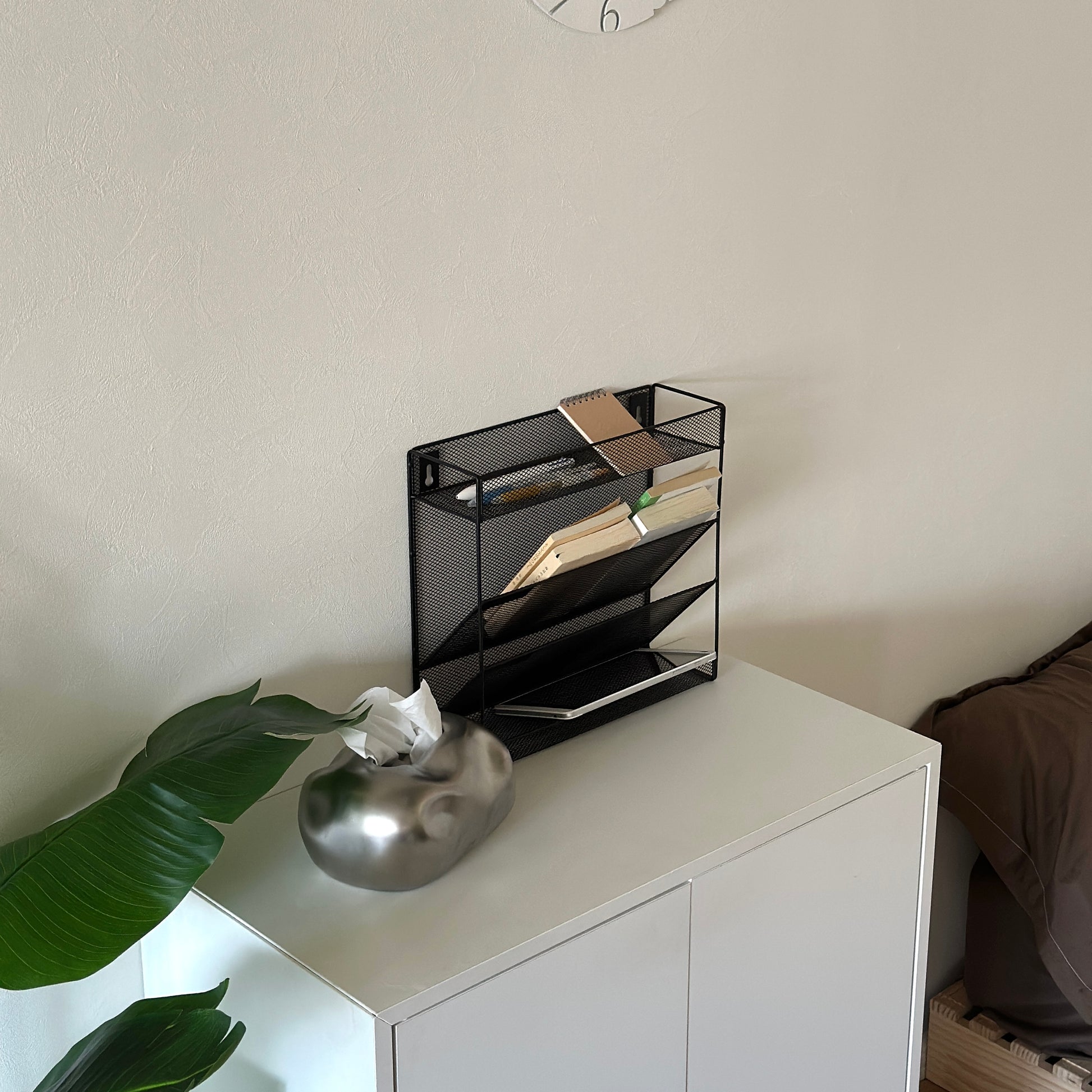 ブラックのメッシュデザインの4段構造ラックが白棚の上に置かれてある様子