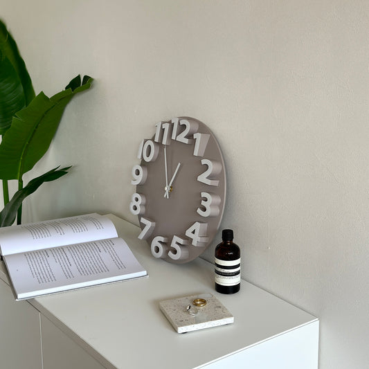 棚の上に置かれた数字が立体的なベージュとホワイトの掛け時計