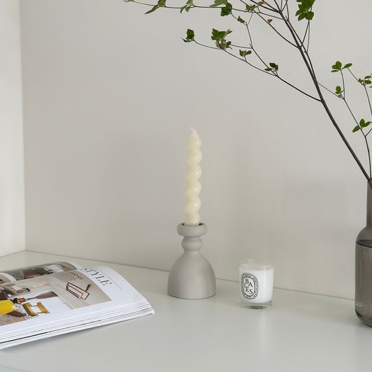 セラミック製マットホワイトのキャンドルホルダーの横にキャンドルや本が置かれている