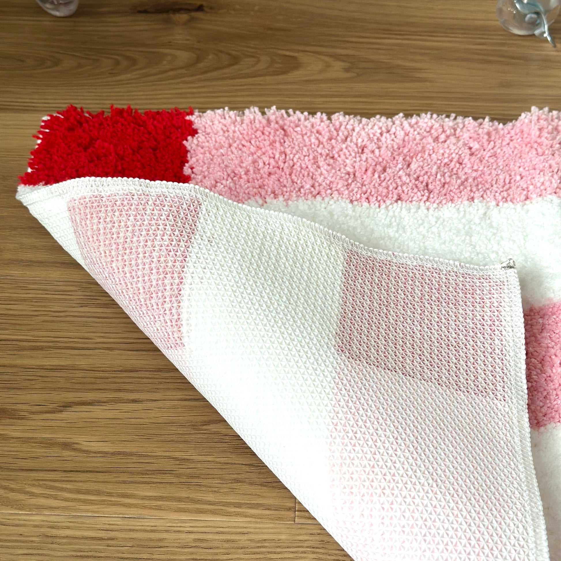 ピンクのブロックカラーが特徴的なミニラグの裏側をめくった様子