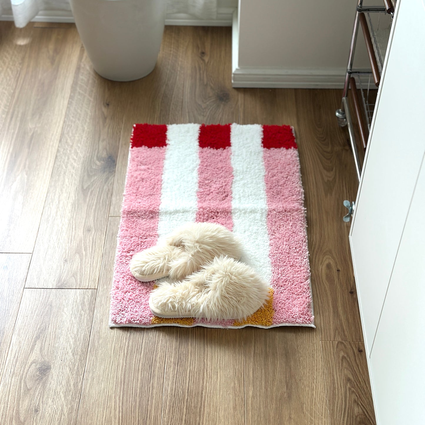 ピンクのブロックカラーが特徴的なミニラグの上にファースリッパが置かれてある様子