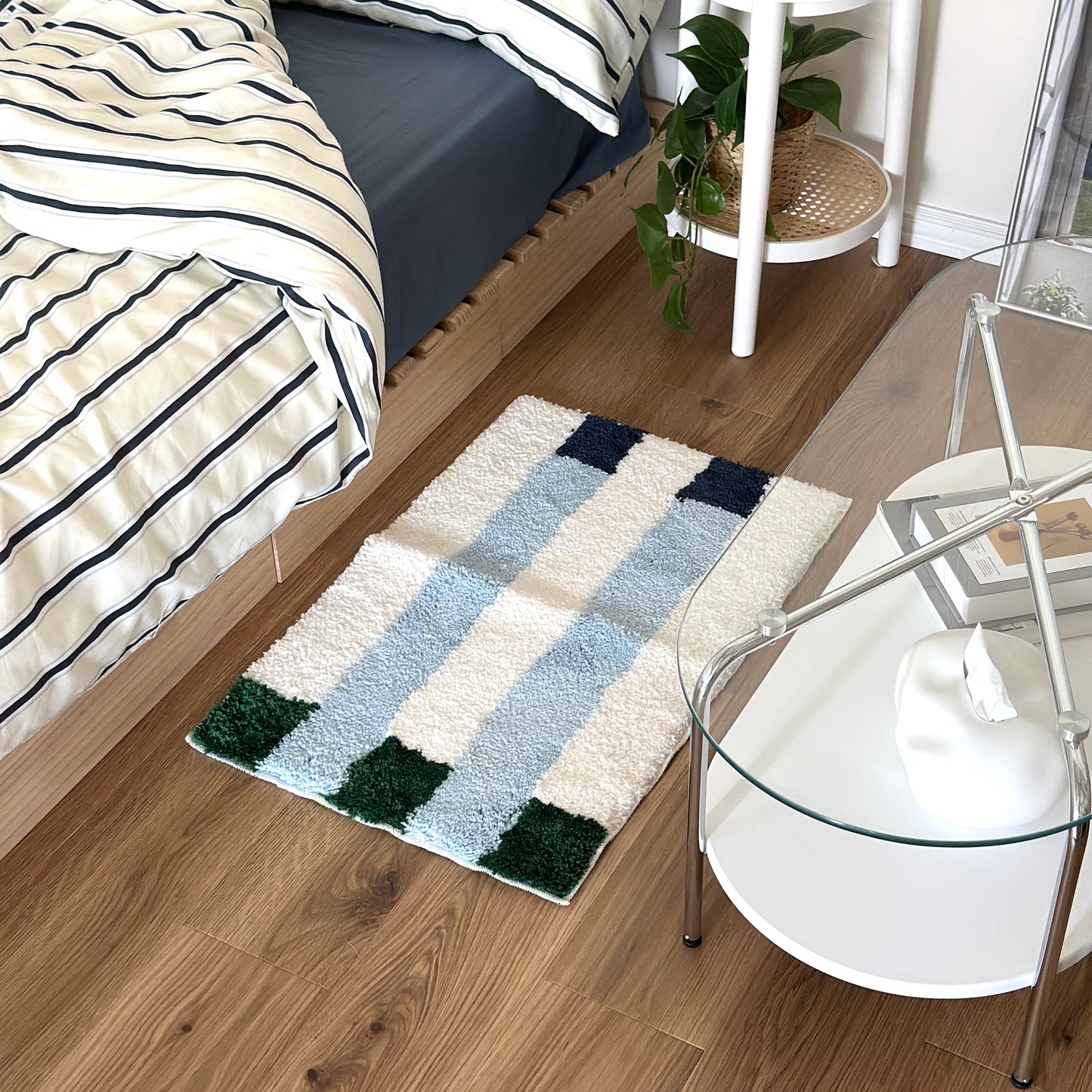 ライトブルーのカラーブロックが特徴的なミニラグをベッド横に敷いている様子