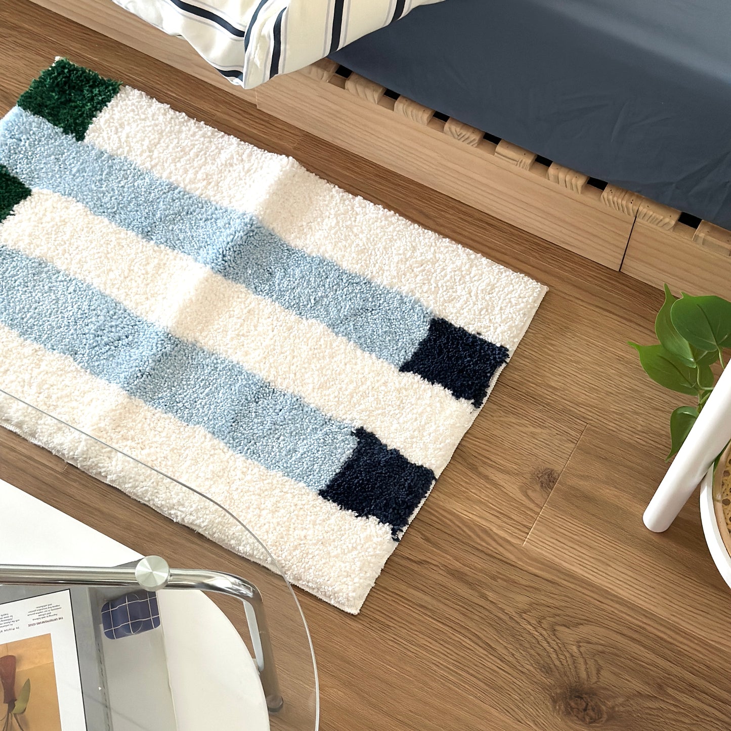 ライトブルーのカラーブロックが特徴的なミニラグをベッド横に敷いている様子