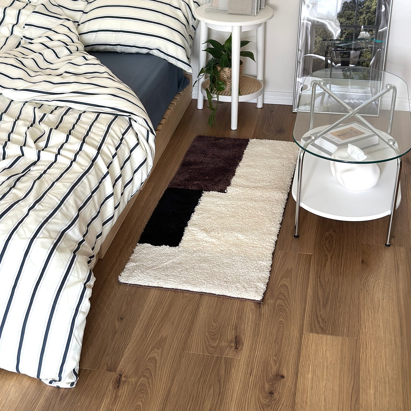 シンプルなブロックカラーのロングラグをベッド横に敷いている様子