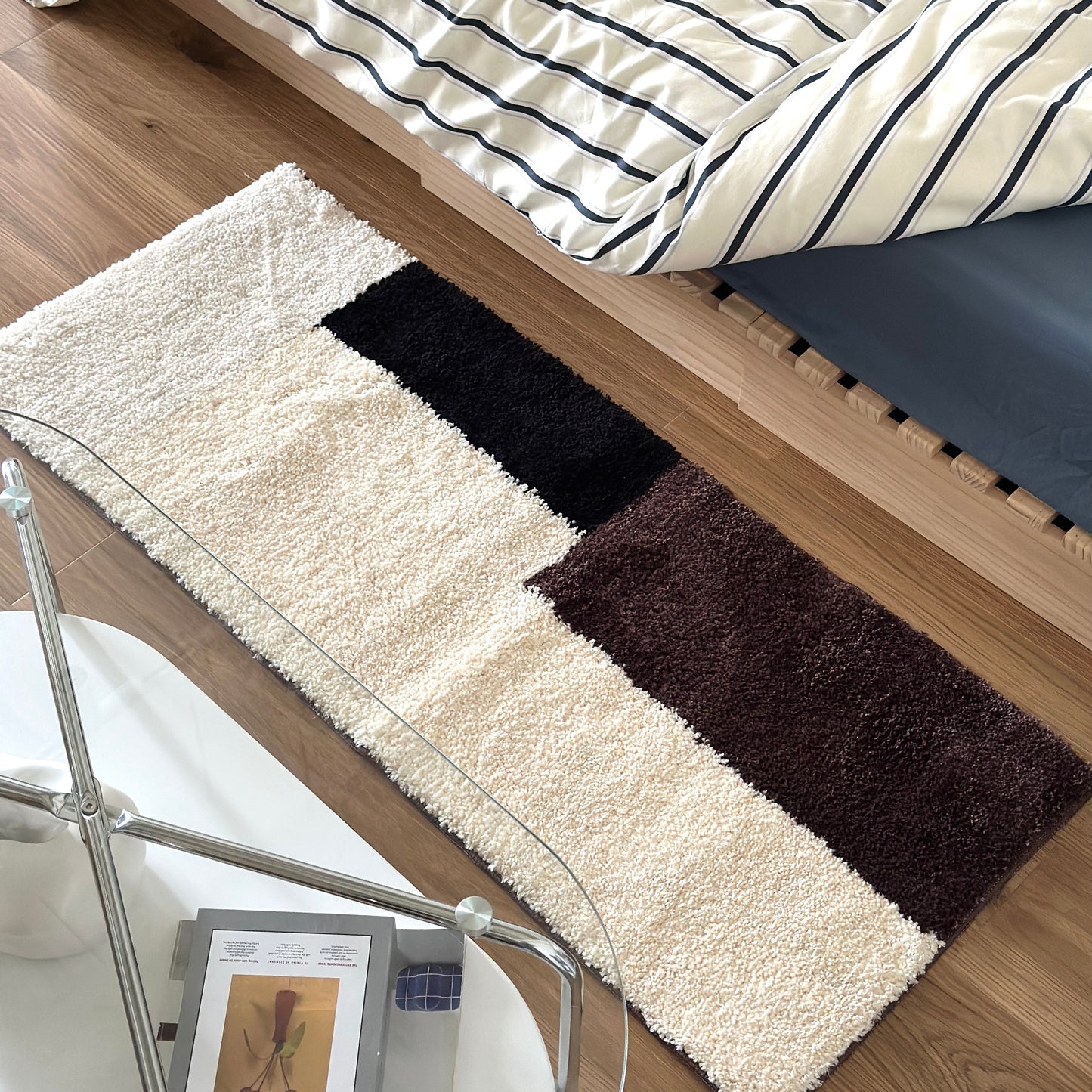 シンプルなブロックカラーのロングラグをベッド横に敷いている様子