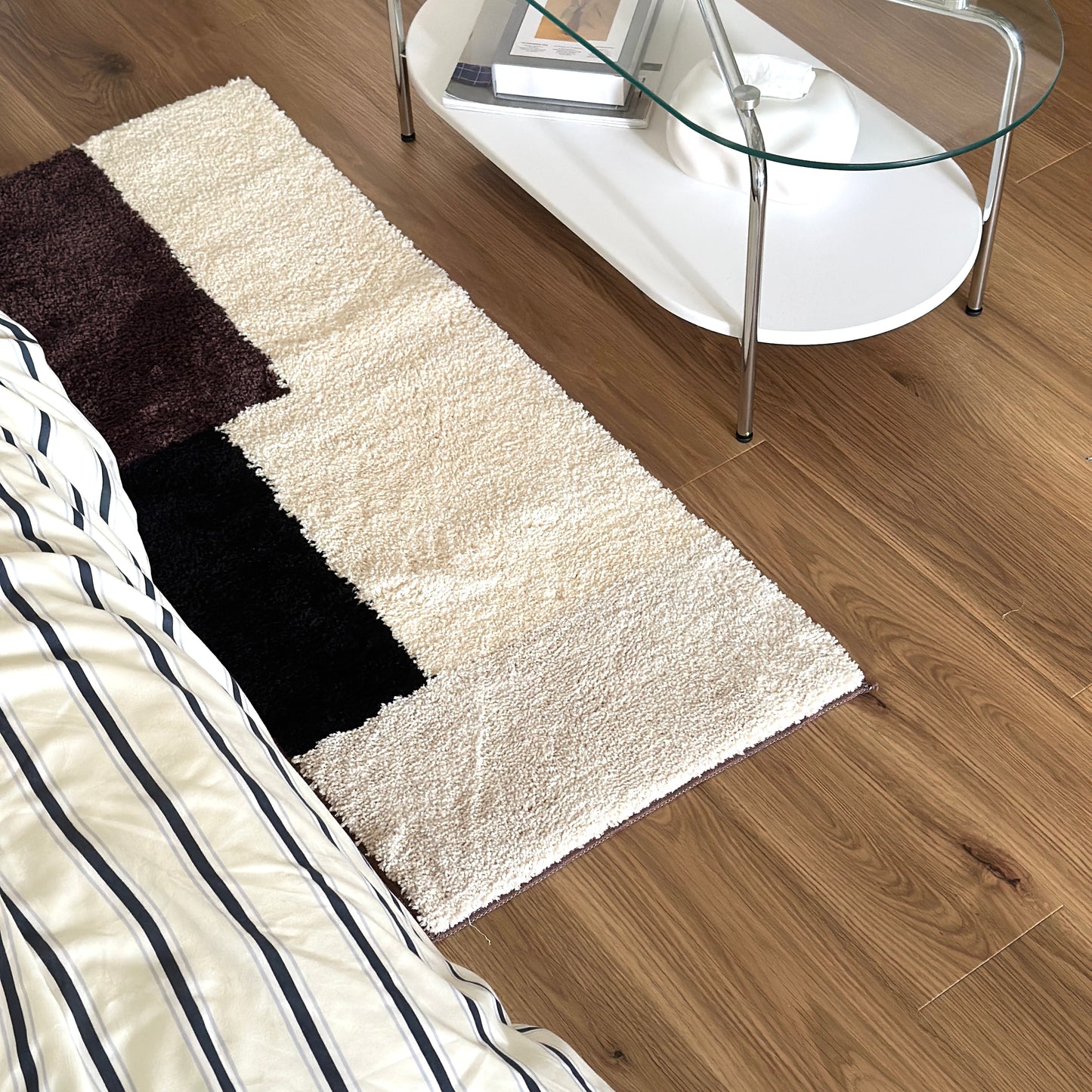 シンプルなブロックカラーのロングラグをベッド横に敷いている様子