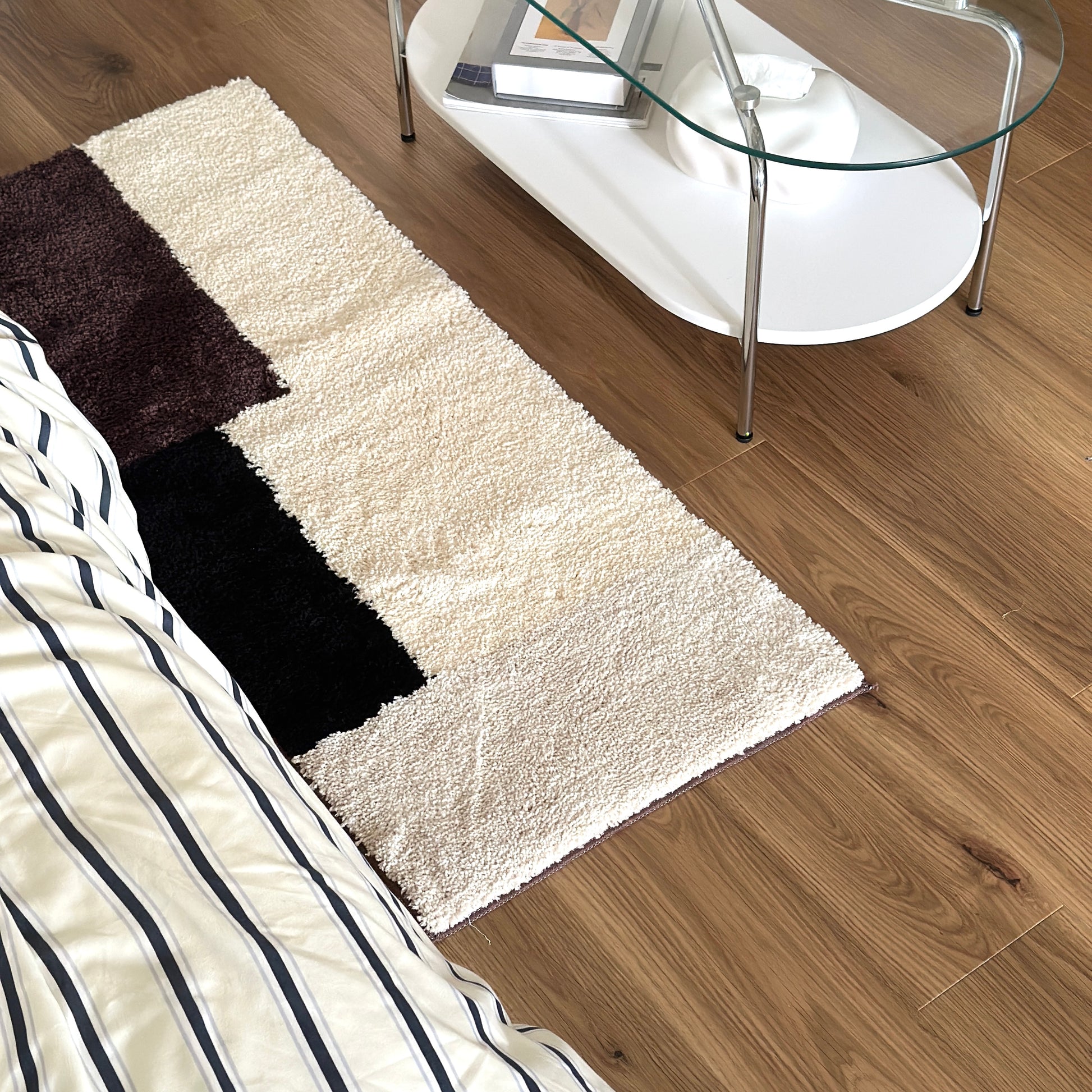 シンプルなブロックカラーのロングラグをベッド横に敷いている様子