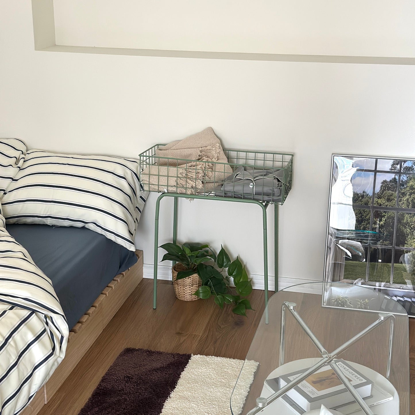 エメラルドのアイアン素材とワイヤーメッシュデザインの収納ワゴンにパジャマとブランケットが入っている様子