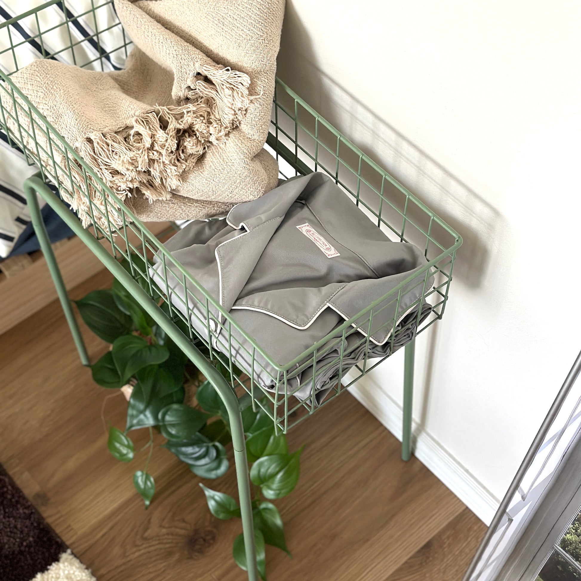 エメラルドのアイアン素材とワイヤーメッシュデザインの収納ワゴンにブランケットとパジャマを入れている様子