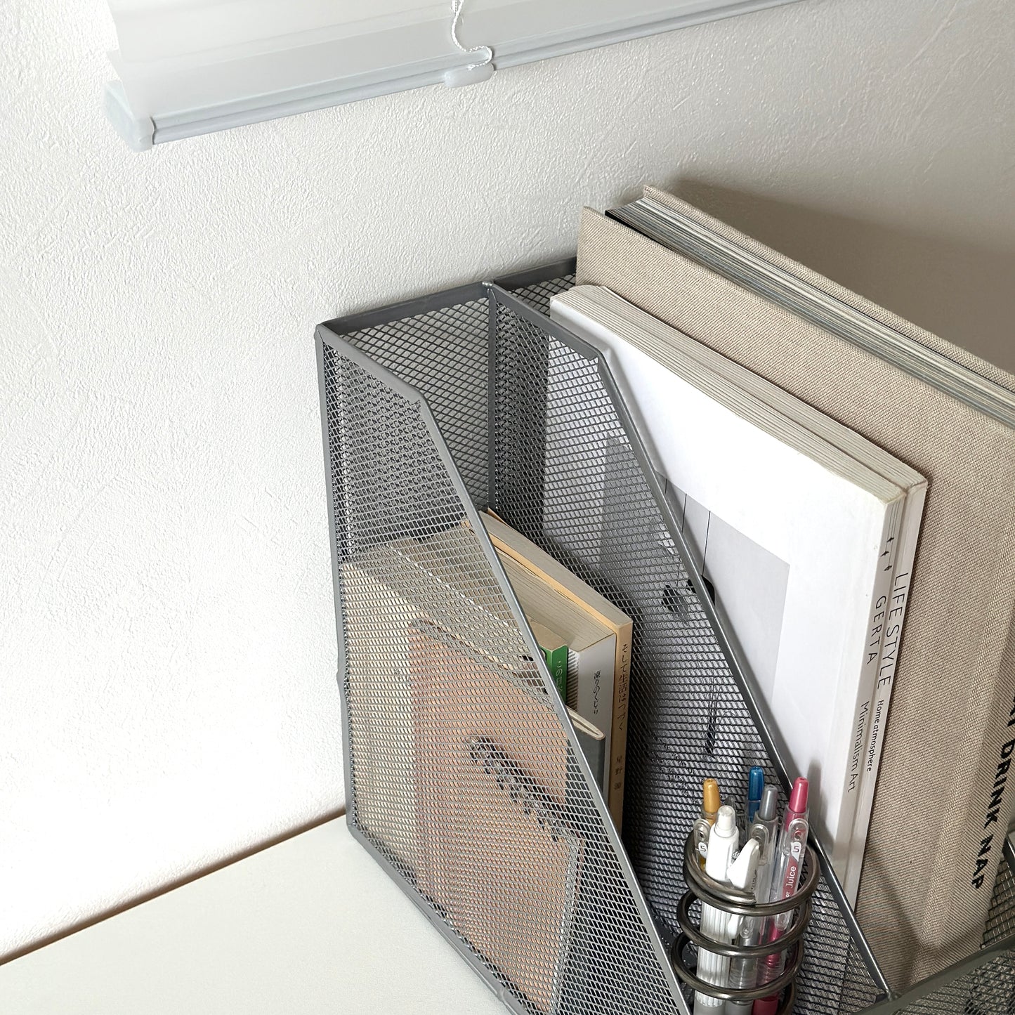 シルバーの卓上ブック収納ラックにペンや文庫本、雑誌を入れている様子