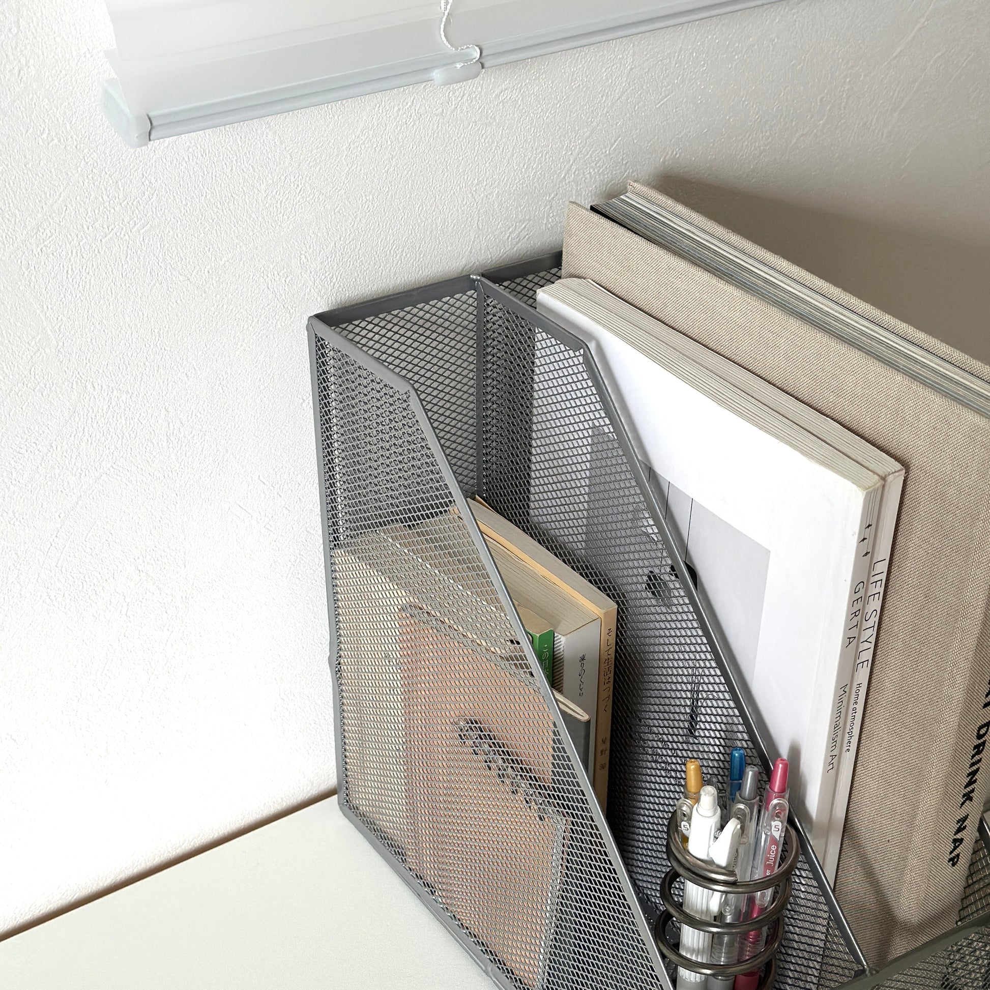 シルバーの卓上ブック収納ラックにペンや文庫本、雑誌を入れている様子