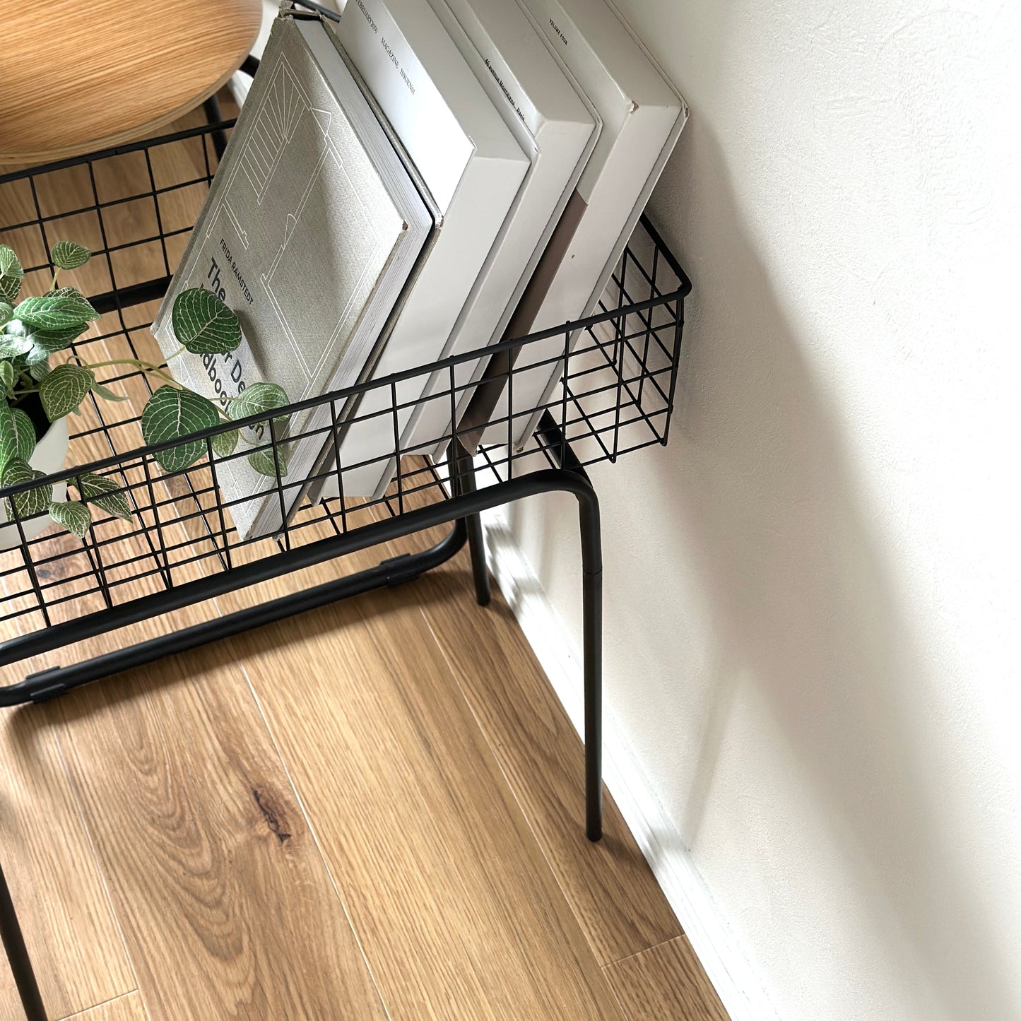 ブラックのアイアン素材とワイヤーメッシュデザインの収納ワゴンに本と植物を入れている様子
