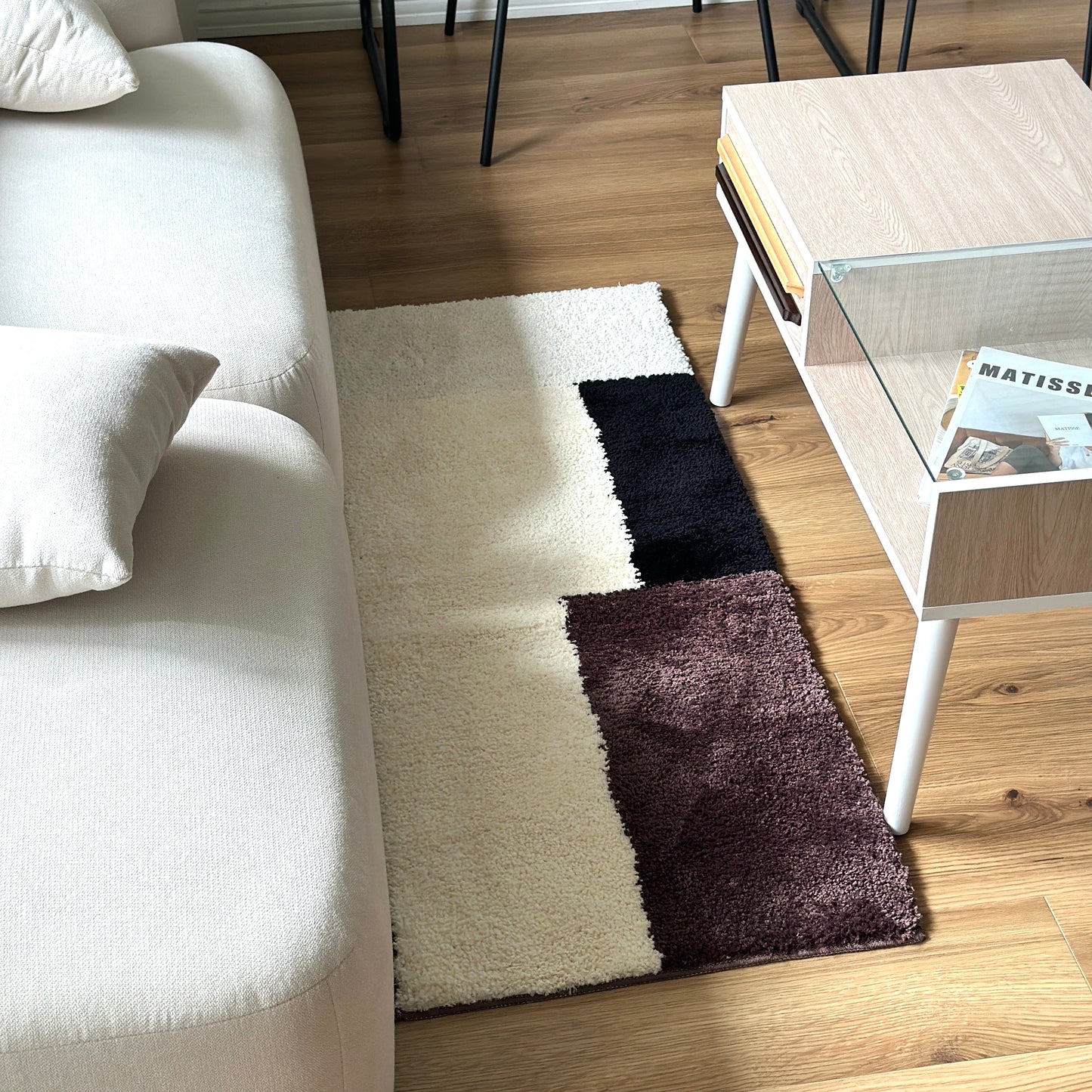 シンプルなブロックカラーのロングラグをソファ前に敷いている様子