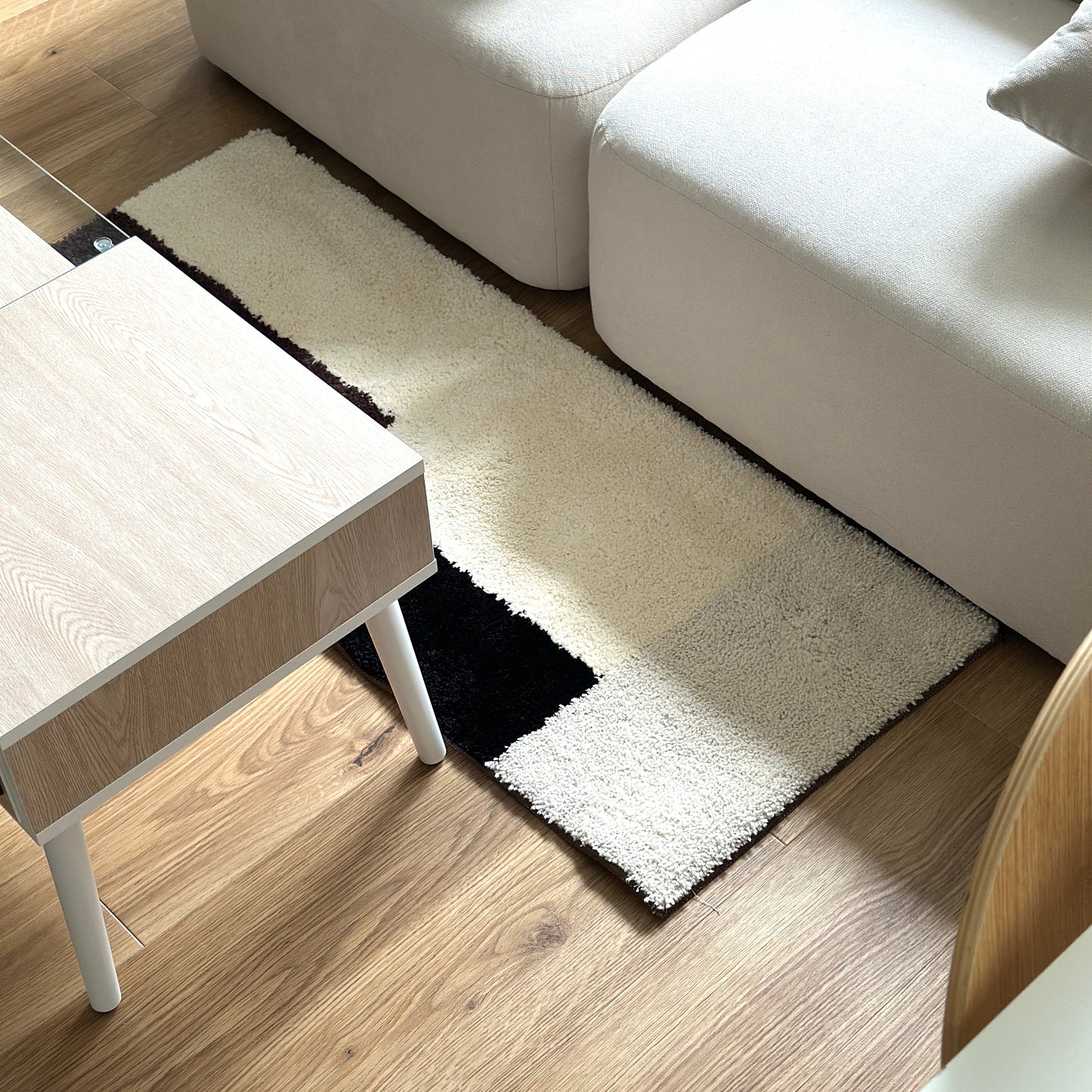 シンプルなブロックカラーのロングラグをソファ前に敷いている様子