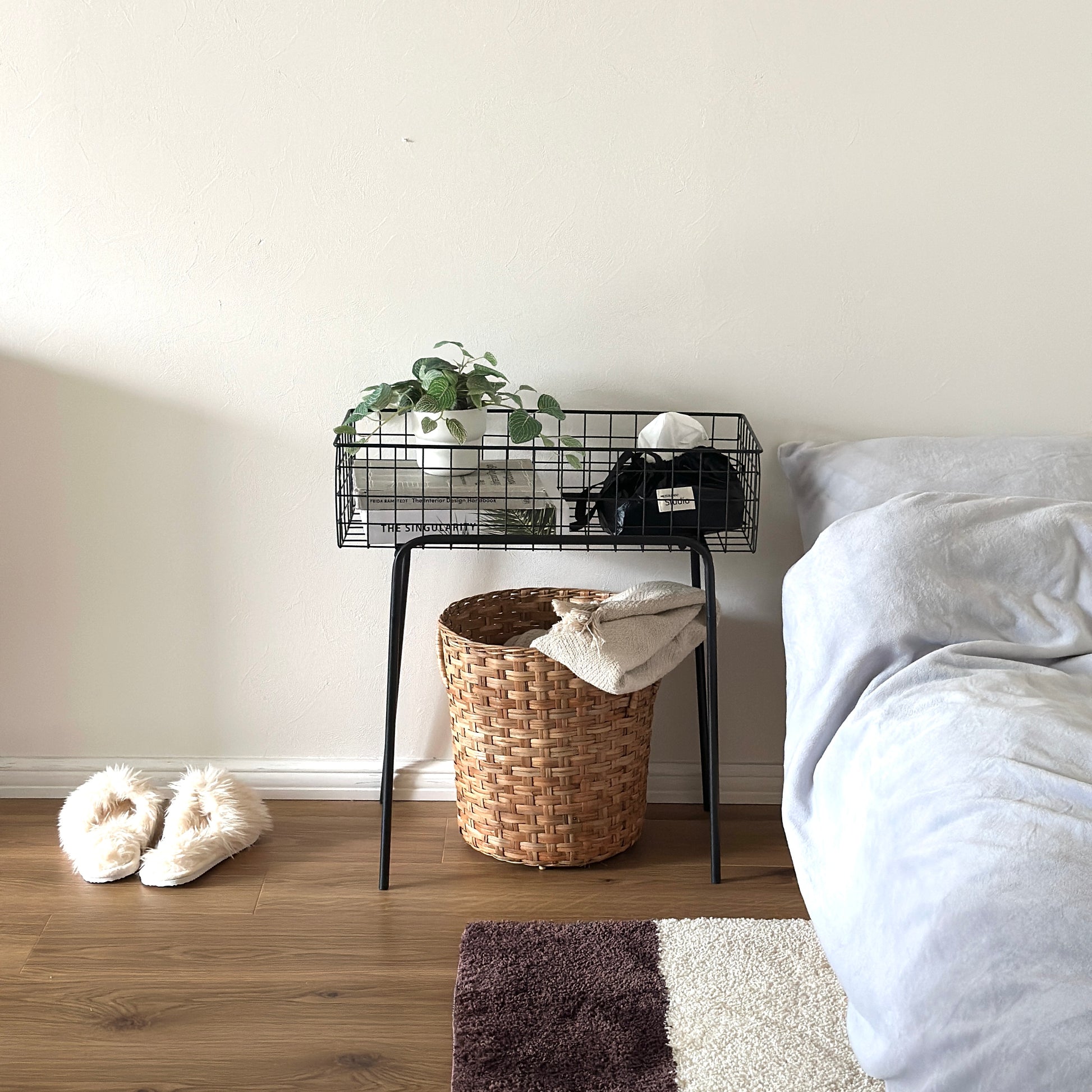 ブラックのアイアン素材とワイヤーメッシュデザインの収納ワゴンをベッド横に置いている様子