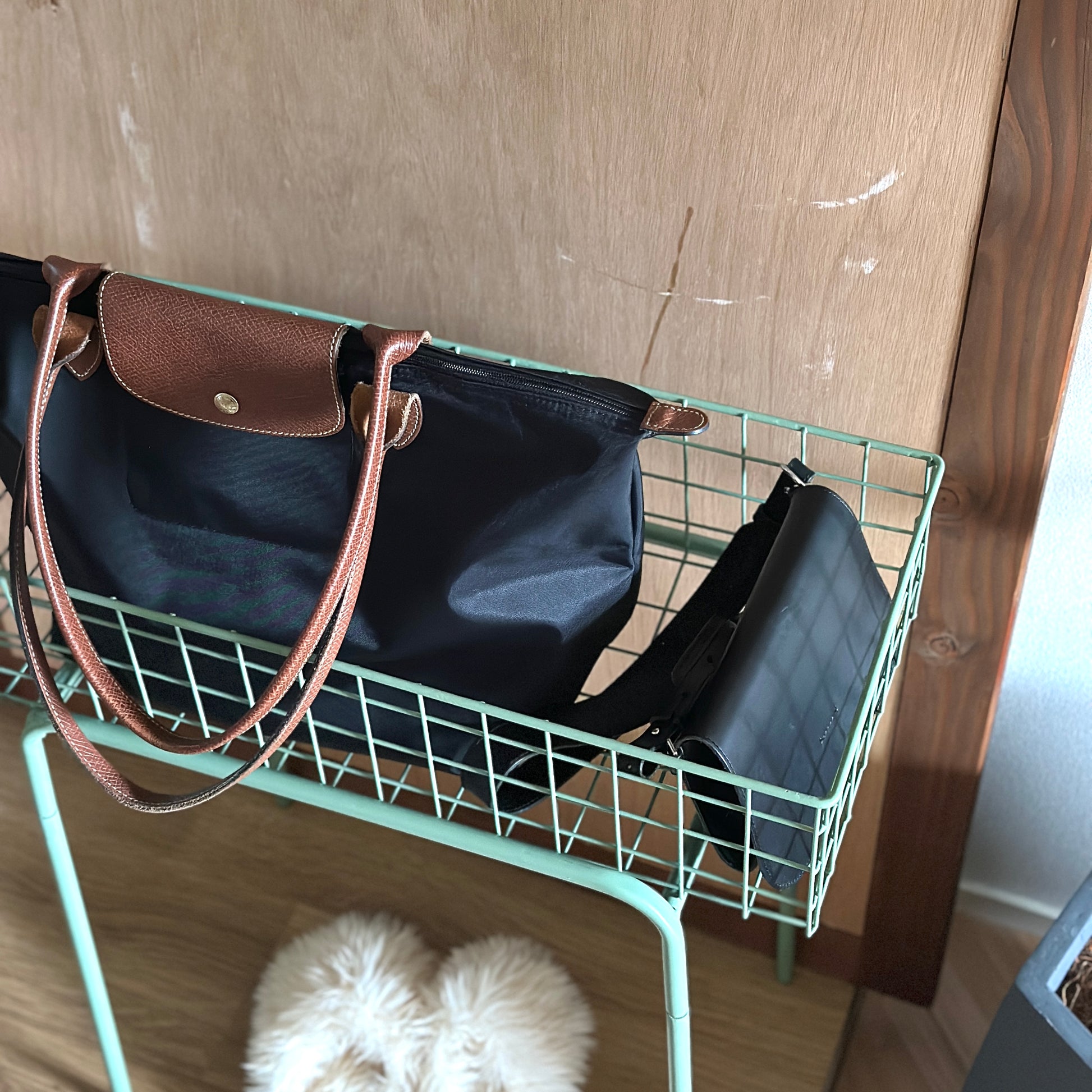 エメラルドのアイアン素材とワイヤーメッシュデザインの収納ワゴンにバッグを入れている様子