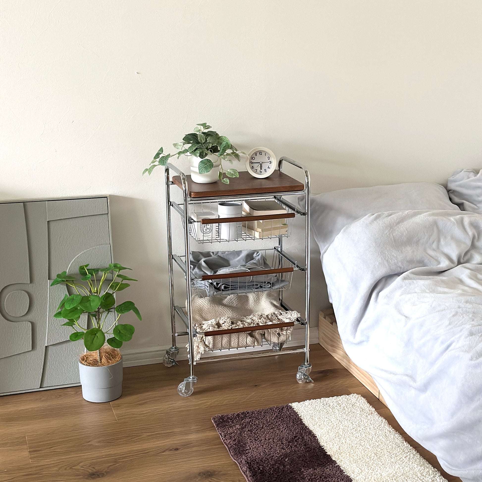ステンレスとウッド天板の収納ワゴンをベッド横に置いている様子
