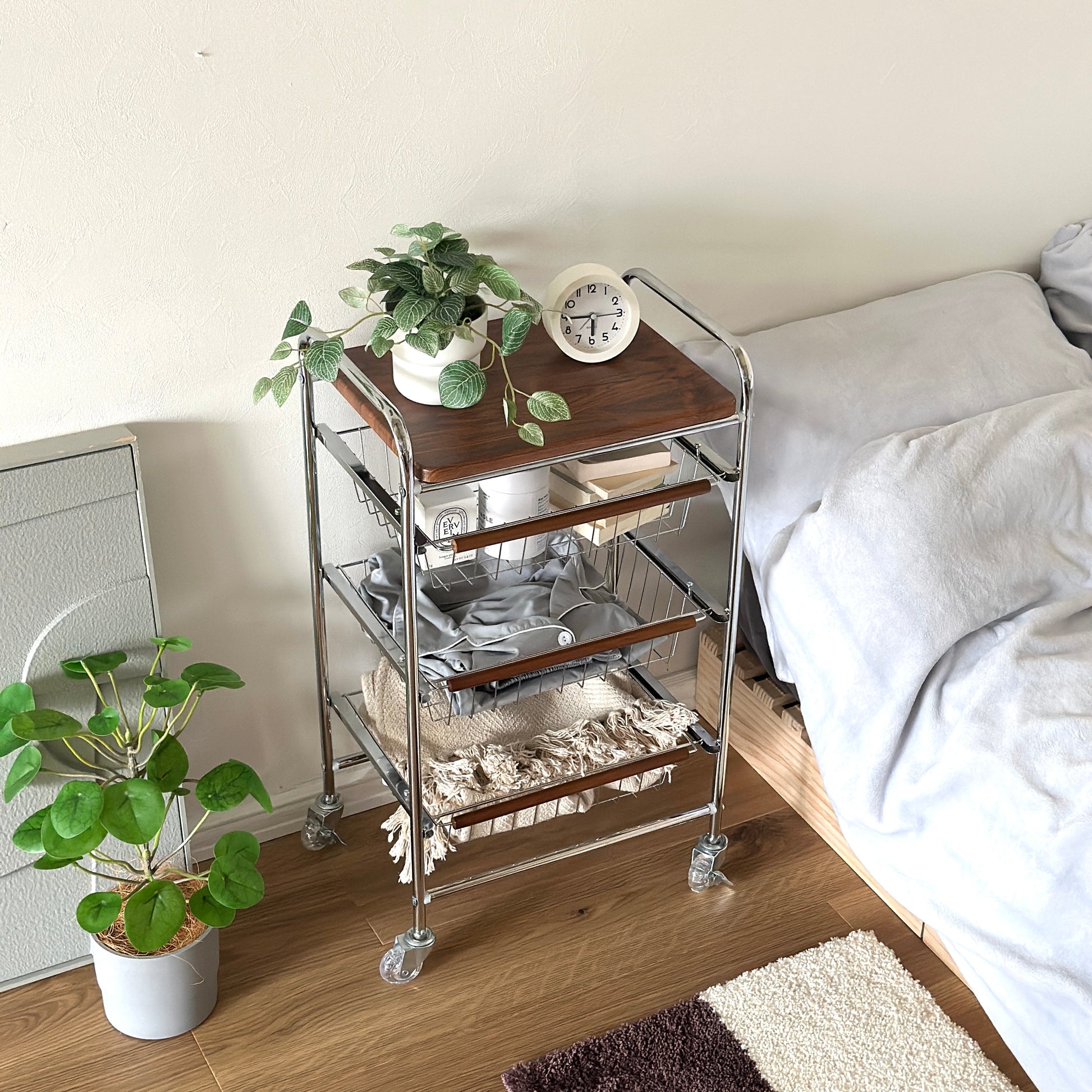 ステンレスとウッド天板の収納ワゴンをベッド横に置いている様子