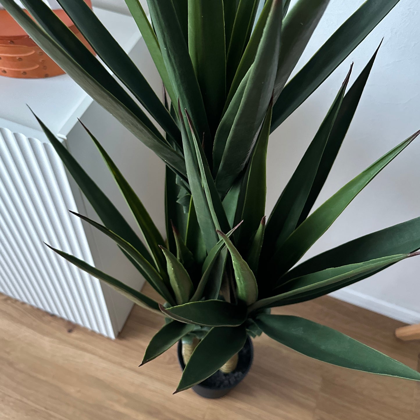 フェイクグリーンユッカの黒い鉢に入った背の高い濃い緑色のとがった葉の人工植物です。