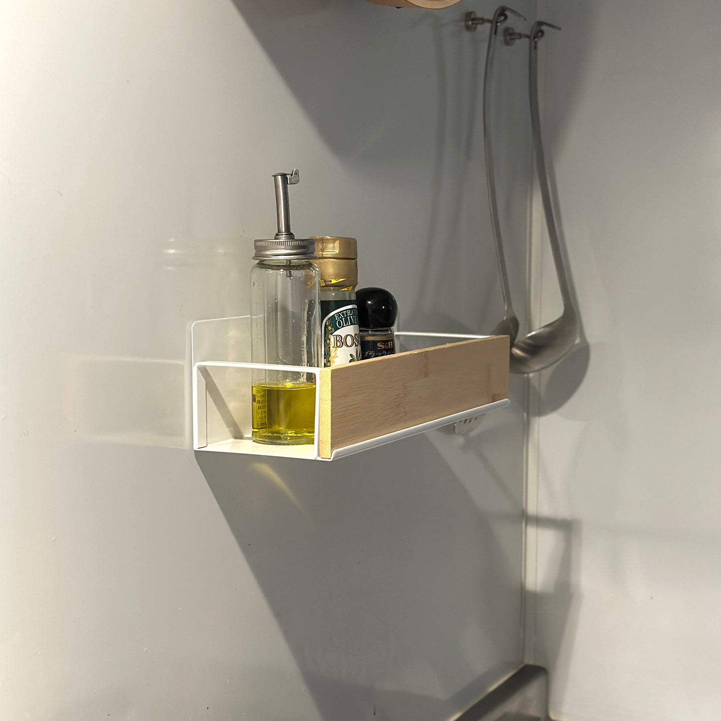 キッチン調味料ラックをキッチンの壁に貼り付けしている様子