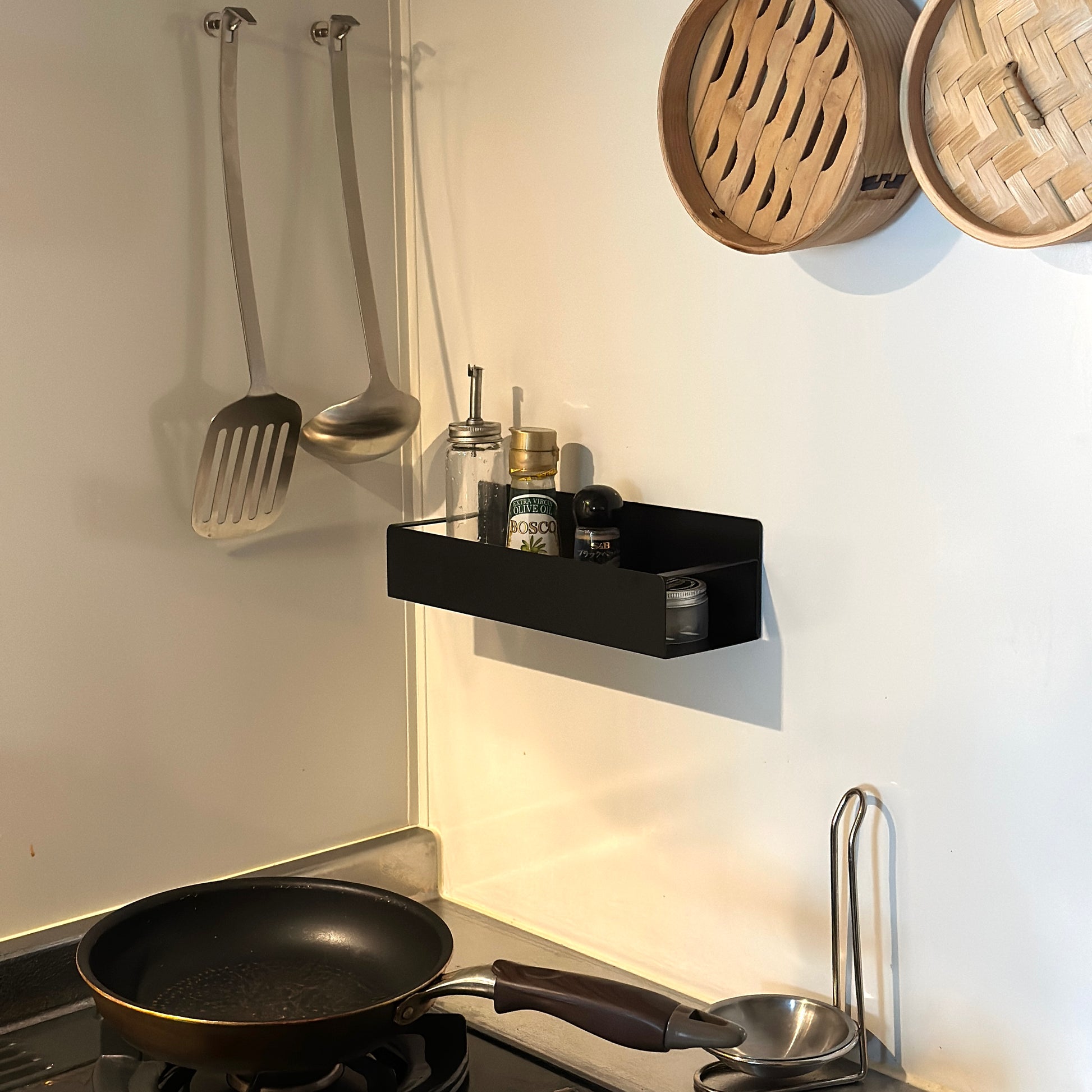 シンプル調味料ラックをキッチンの壁に貼り付けしている様子