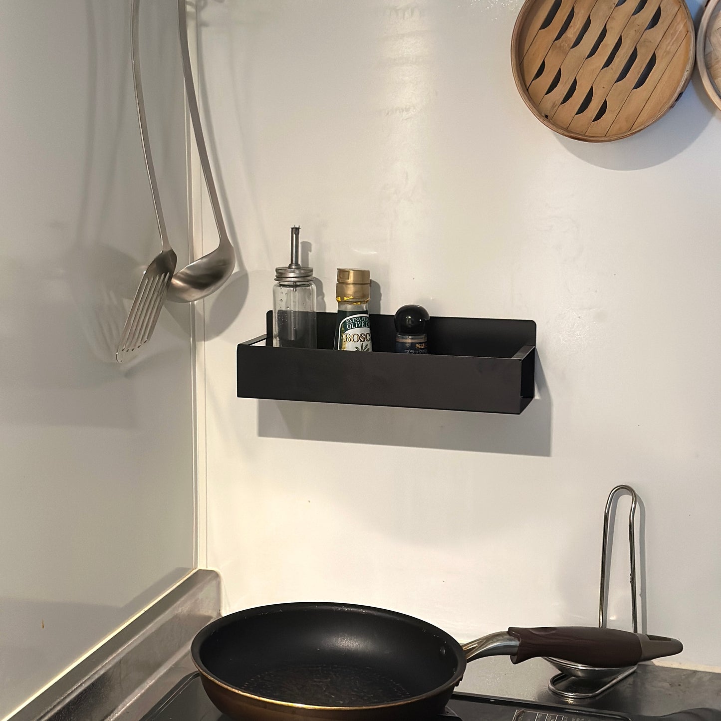 シンプル調味料ラックをキッチンの壁に貼り付けしている様子