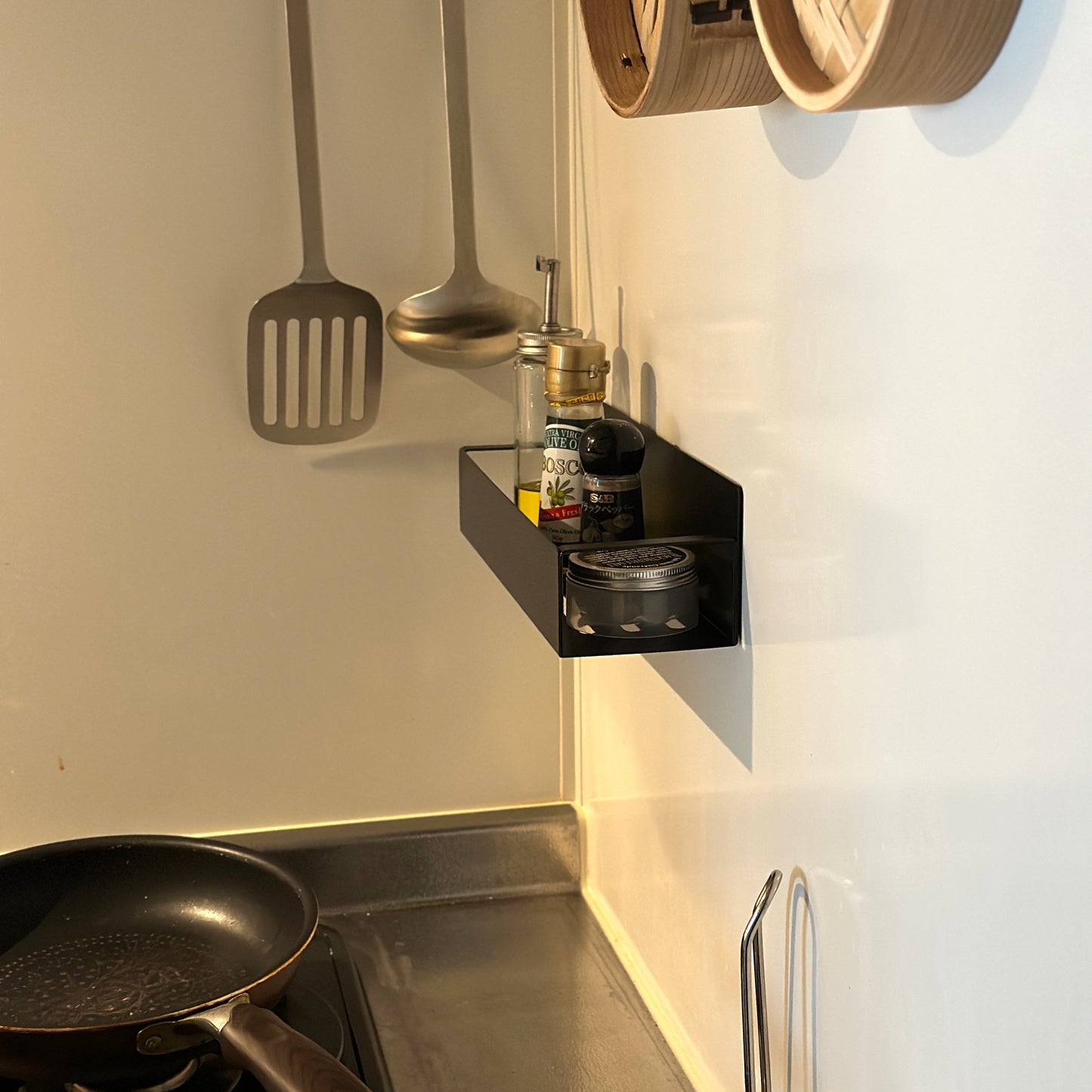 シンプル調味料ラックをキッチンの壁に貼り付けしている様子