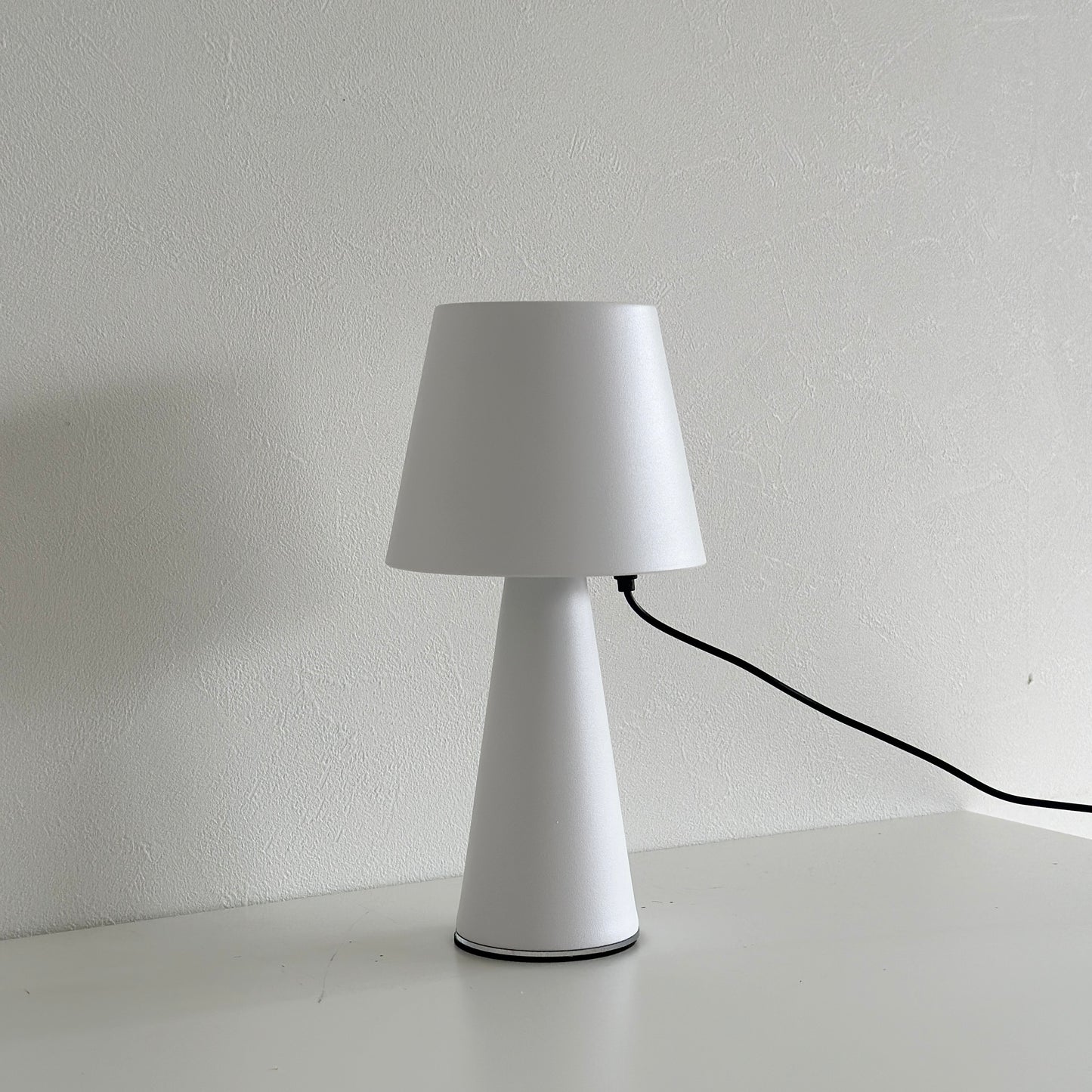 マット素材のシンプルな白色のテーブルランプが充電されている様子