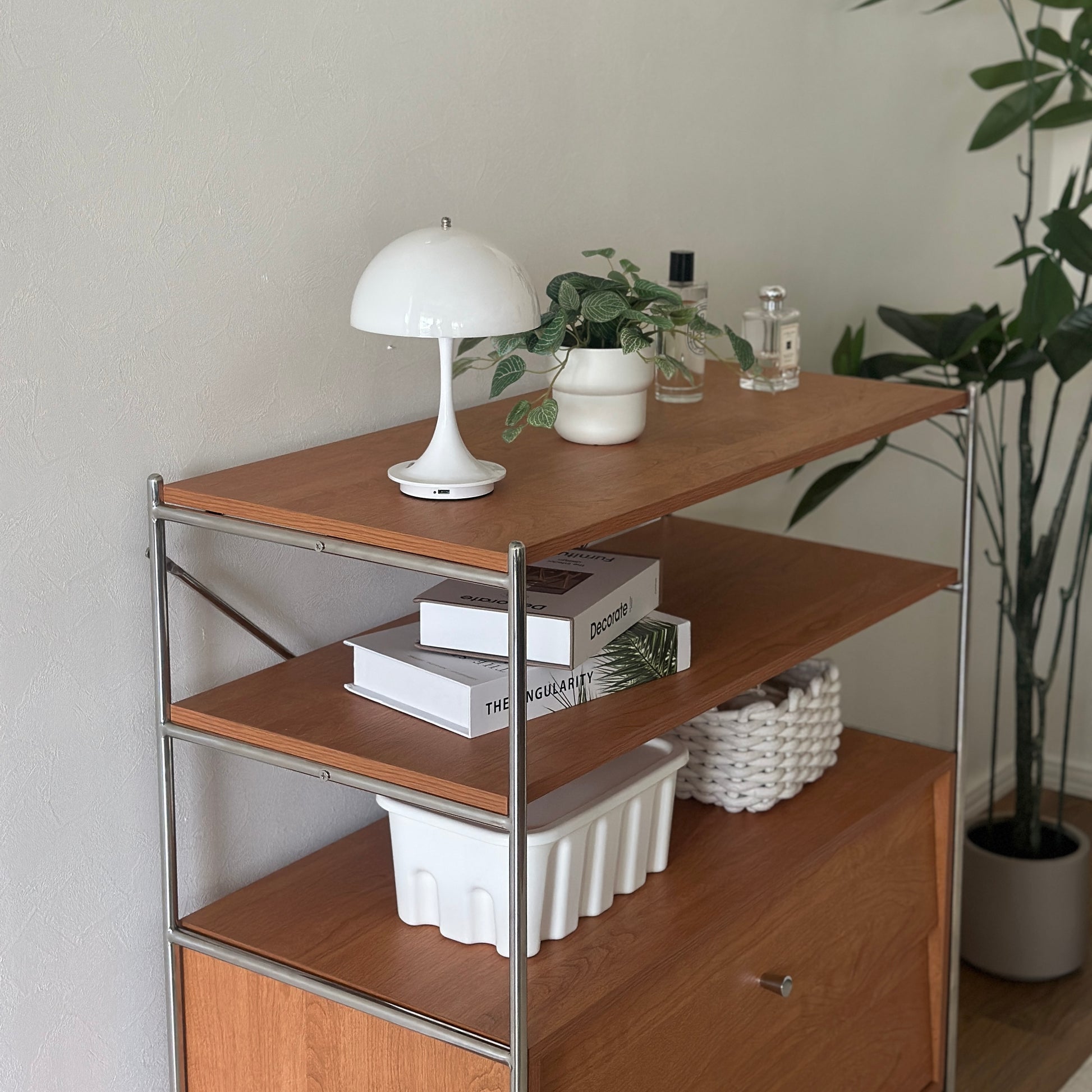 ウッド×アイアン製の引き出しシェルフにライトや植物、香水、本、収納ボックスが置かれてある様子