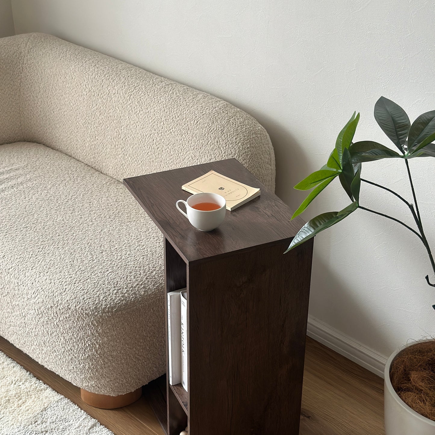 ブラウンの2way置きサイドテーブルに文庫本とコップを置いている様子