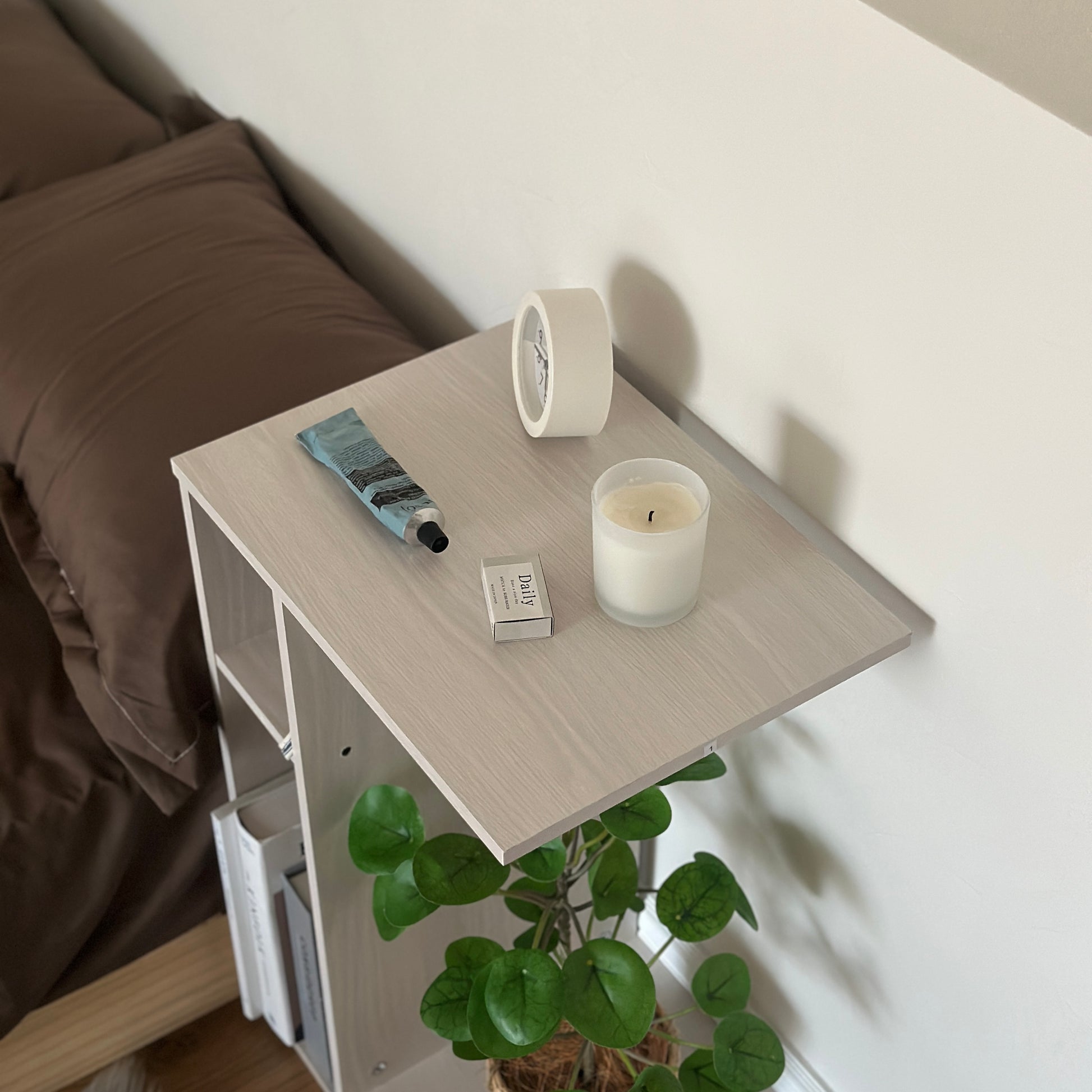 ホワイトの2way置きサイドテーブルに置き時計やキャンドル、ハンドクリームなどを置いている様子