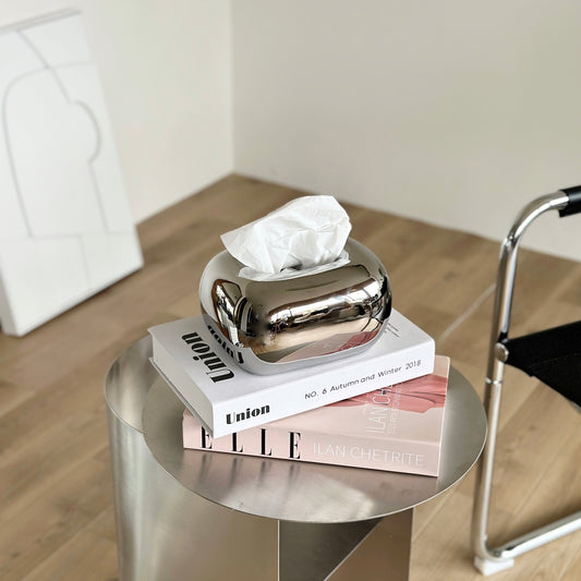 2冊の雑誌の上にシルバーのティッシュケースが置かれてある様子