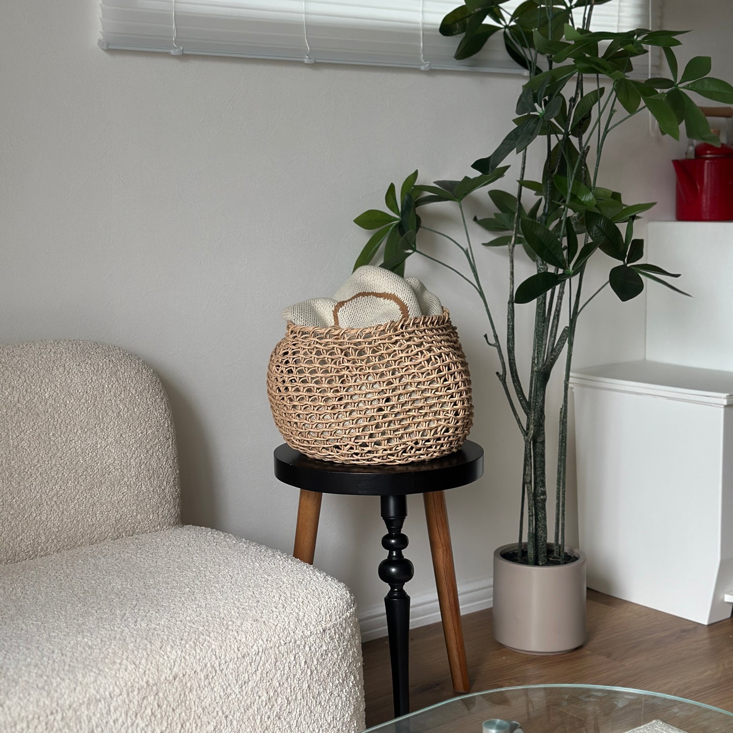 ラウンドのペーパーコードバスケットの中にブランケットを入れて、ソファ横のサイドテーブル上に置いている様子