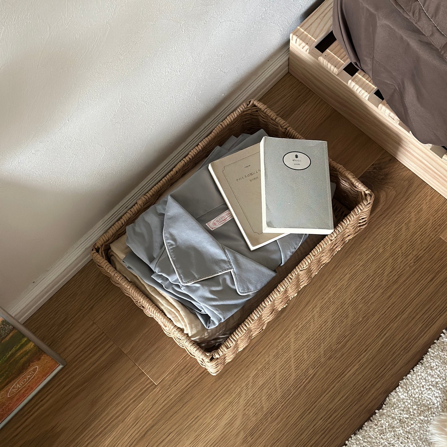 手編みの折り畳み式ペーパーコードバスケットの中にパジャマや文庫本が入っている様子