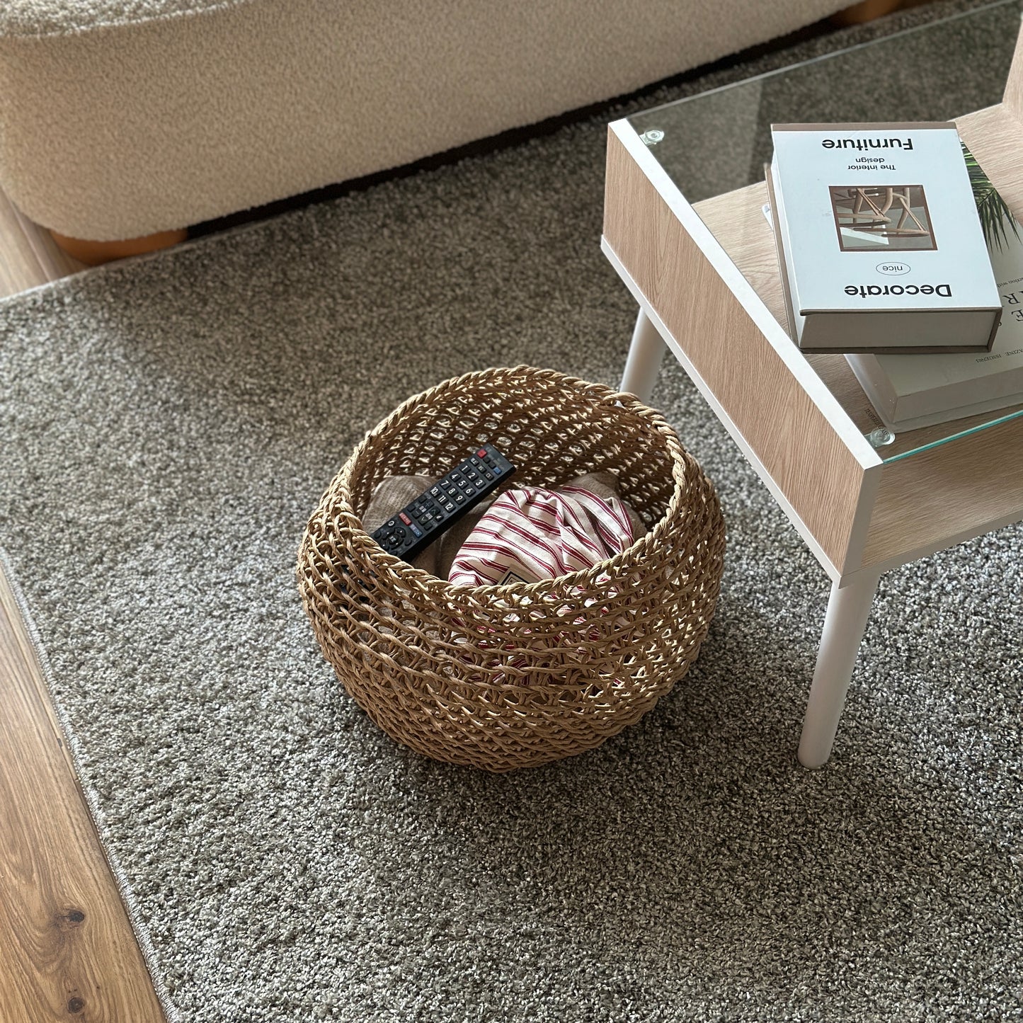 ラウンドのペーパーコードバスケットの中にブランケットやリモコンを入れて、ローテーブル横に置いている様子