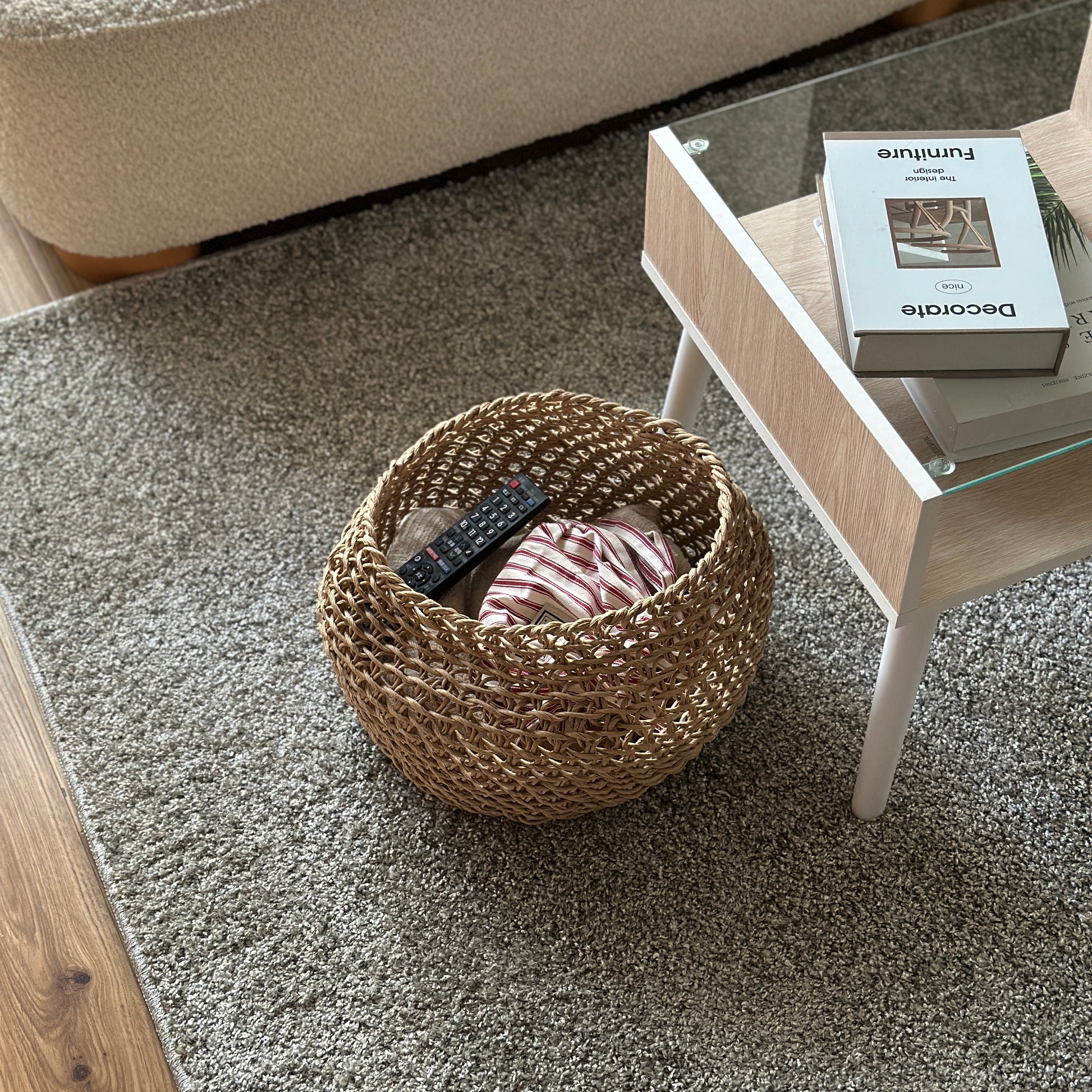 ラウンドのペーパーコードバスケットの中にブランケットやリモコンを入れて、ローテーブル横に置いている様子