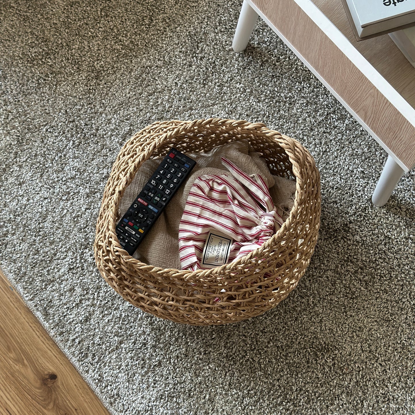 ラウンドのペーパーコードバスケットの中にブランケットやリモコンを入れている様子