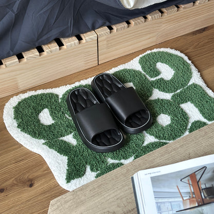 黒のクッション入りのルームスリッパをベッド横のミニラグの上に置いている様子