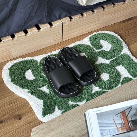 黒のクッション入りのルームスリッパをベッド横のミニラグの上に置いている様子