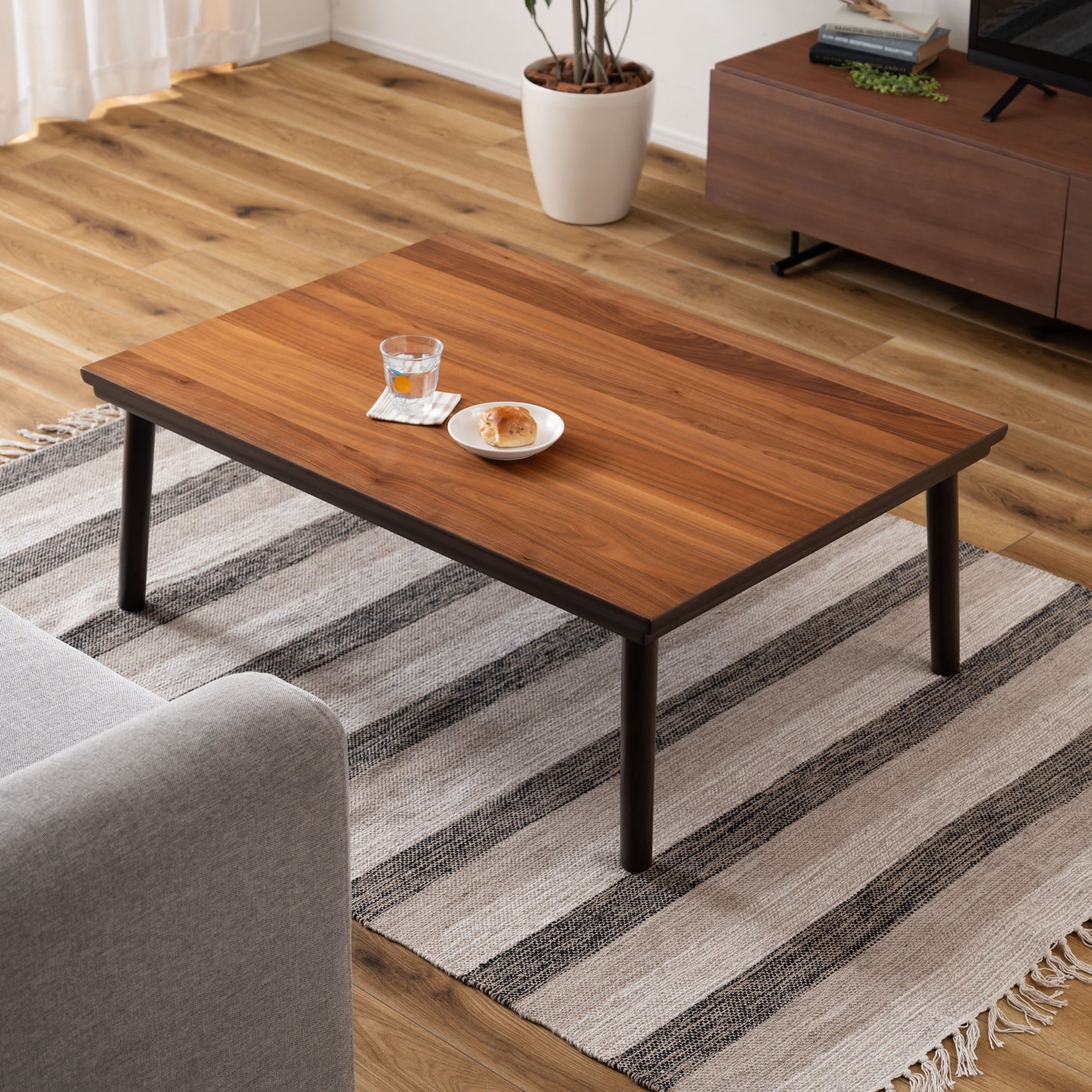 ウォルナットのこたつテーブルにパンとコップが置かれてある様子