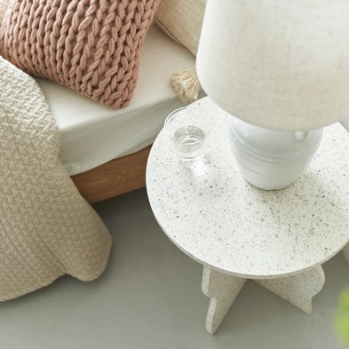 テラゾー柄のウェーブサイドテーブルの上にライトとコップが置いている様子