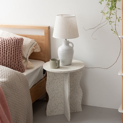 テラゾー柄のウェーブサイドテーブルをベッド横に置いている様子