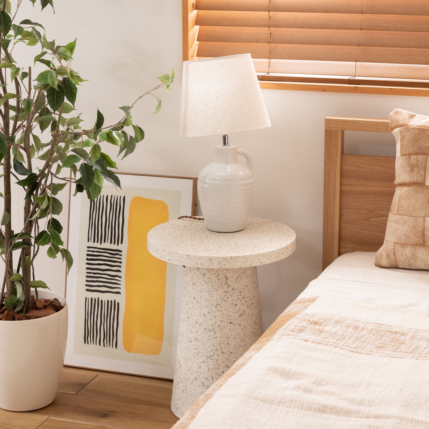 ベッド横にテラゾー柄ラウンドサイドテーブルが置いてある様子