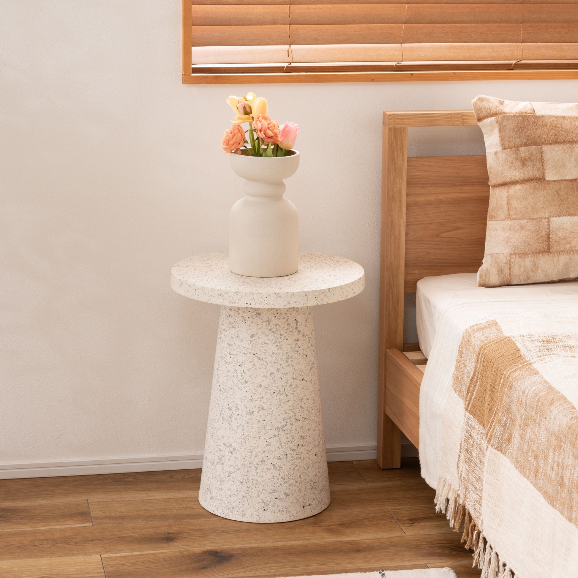 ベッド横にテラゾー柄ラウンドサイドテーブルが置いてある様子