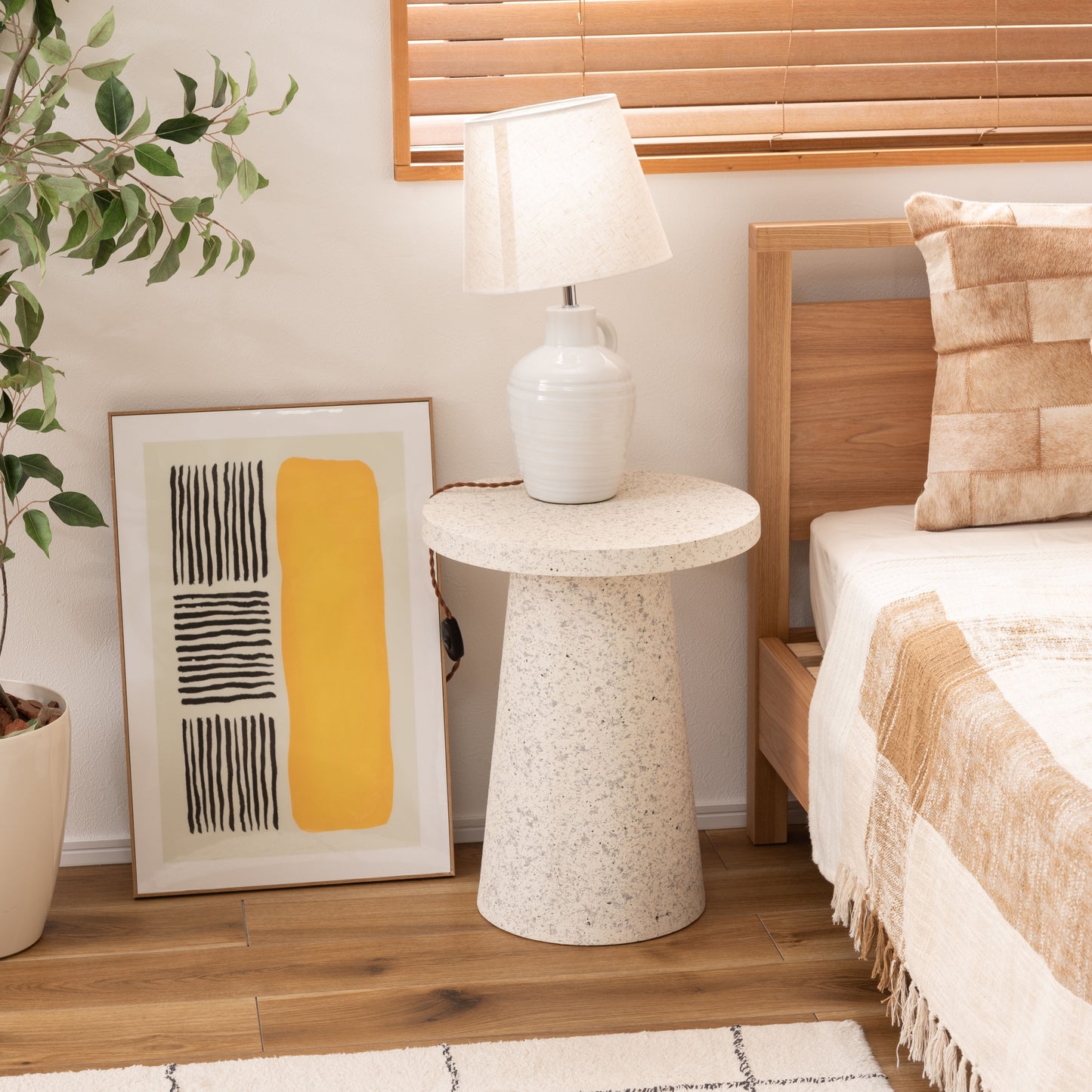 ベッド横にテラゾー柄ラウンドサイドテーブルが置いてある様子