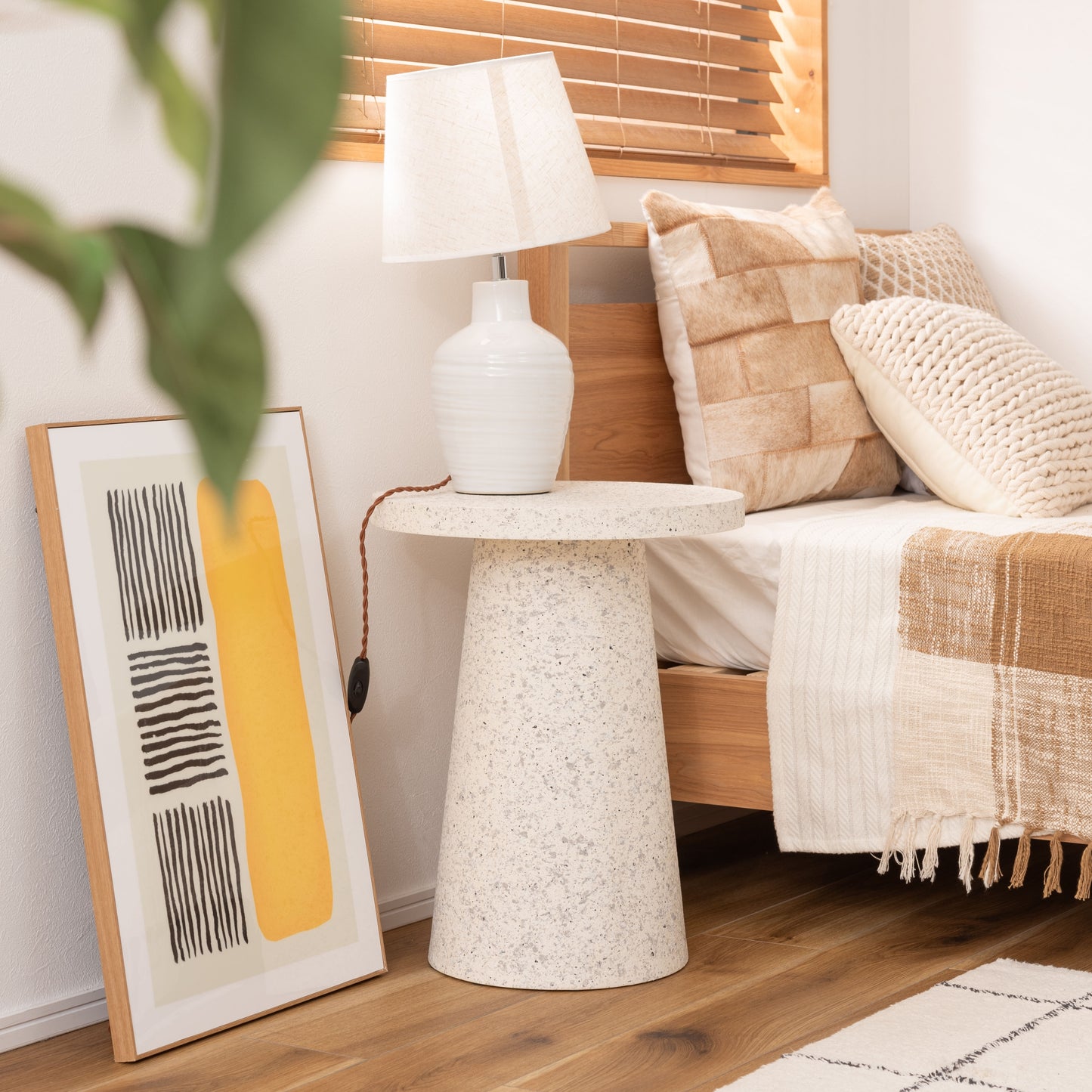 ベッド横にテラゾー柄ラウンドサイドテーブルが置いてある様子