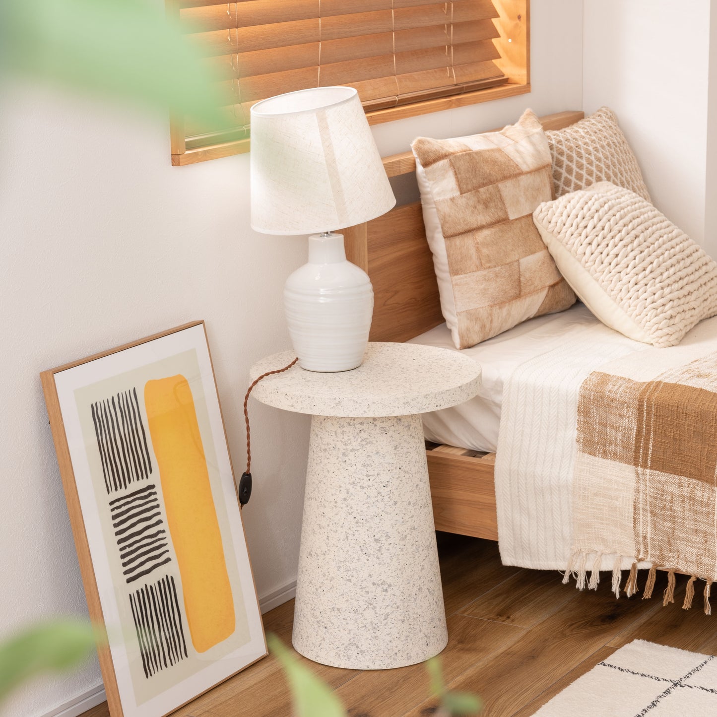 ベッド横にテラゾー柄ラウンドサイドテーブルが置いてある様子